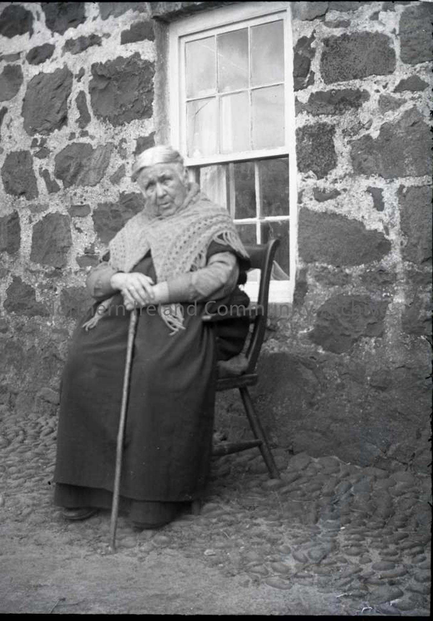 Elderly lady outside a stone cottage