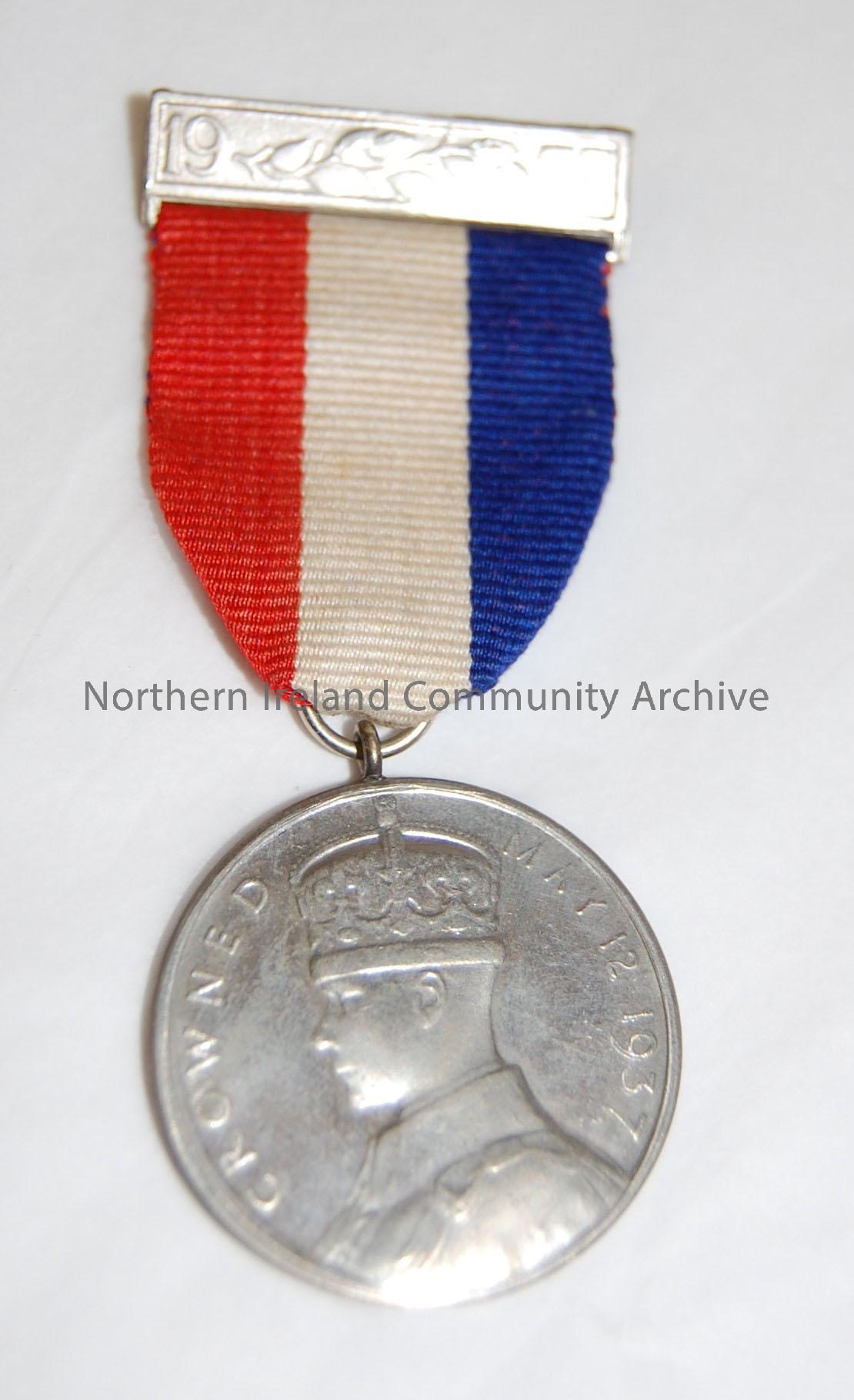 King George VI Coronation medal. Silver coloured base metal medal with original red, white,and blue ribbon with original pin. – 1992.273 (2)