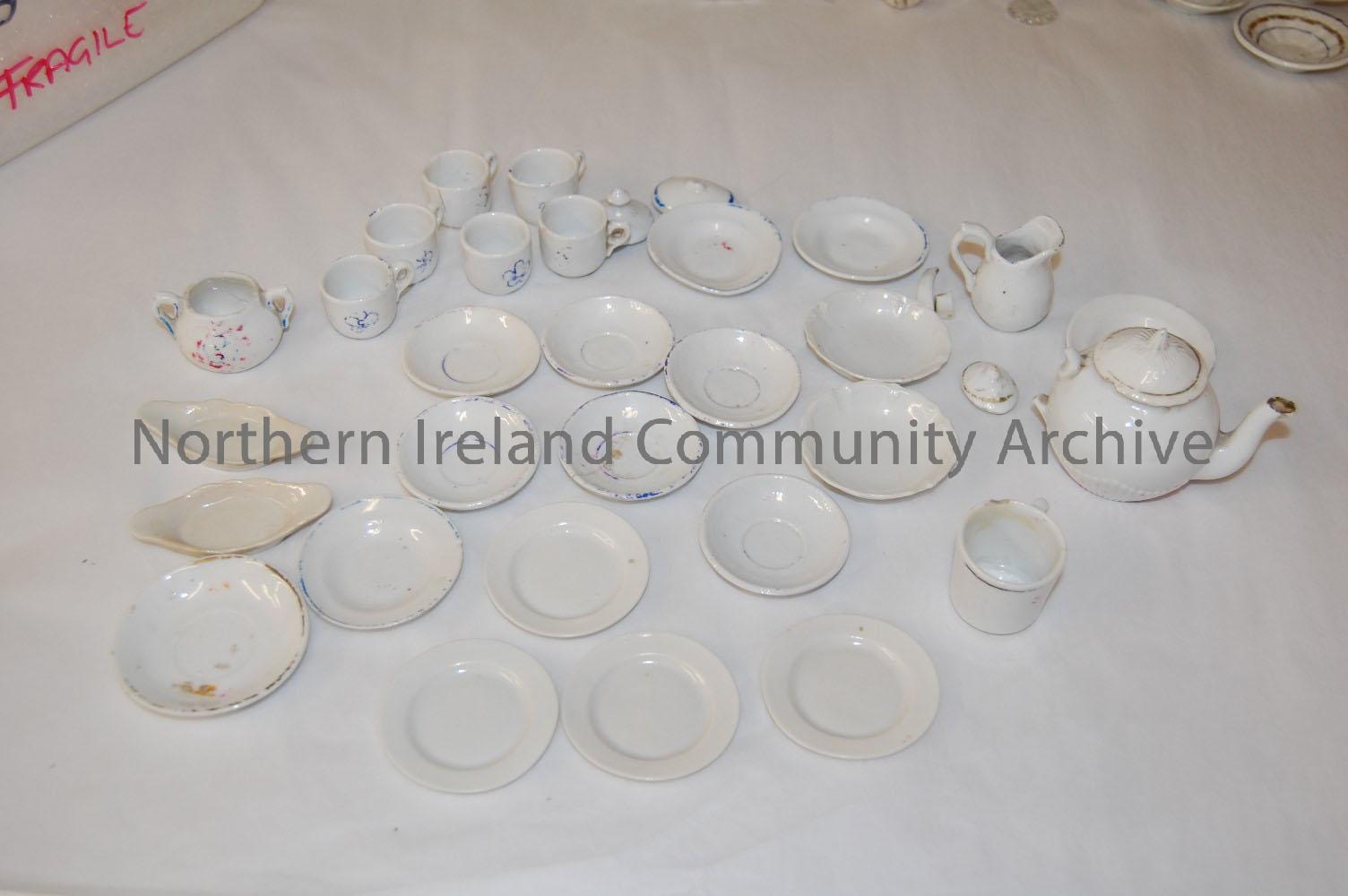 teapot, milk jug, sugar bowl, cups (5no.), saucers (3no.) cake stand, forks (4no.), knives (3no.), spoons (4no.) – 1997.8 (2)