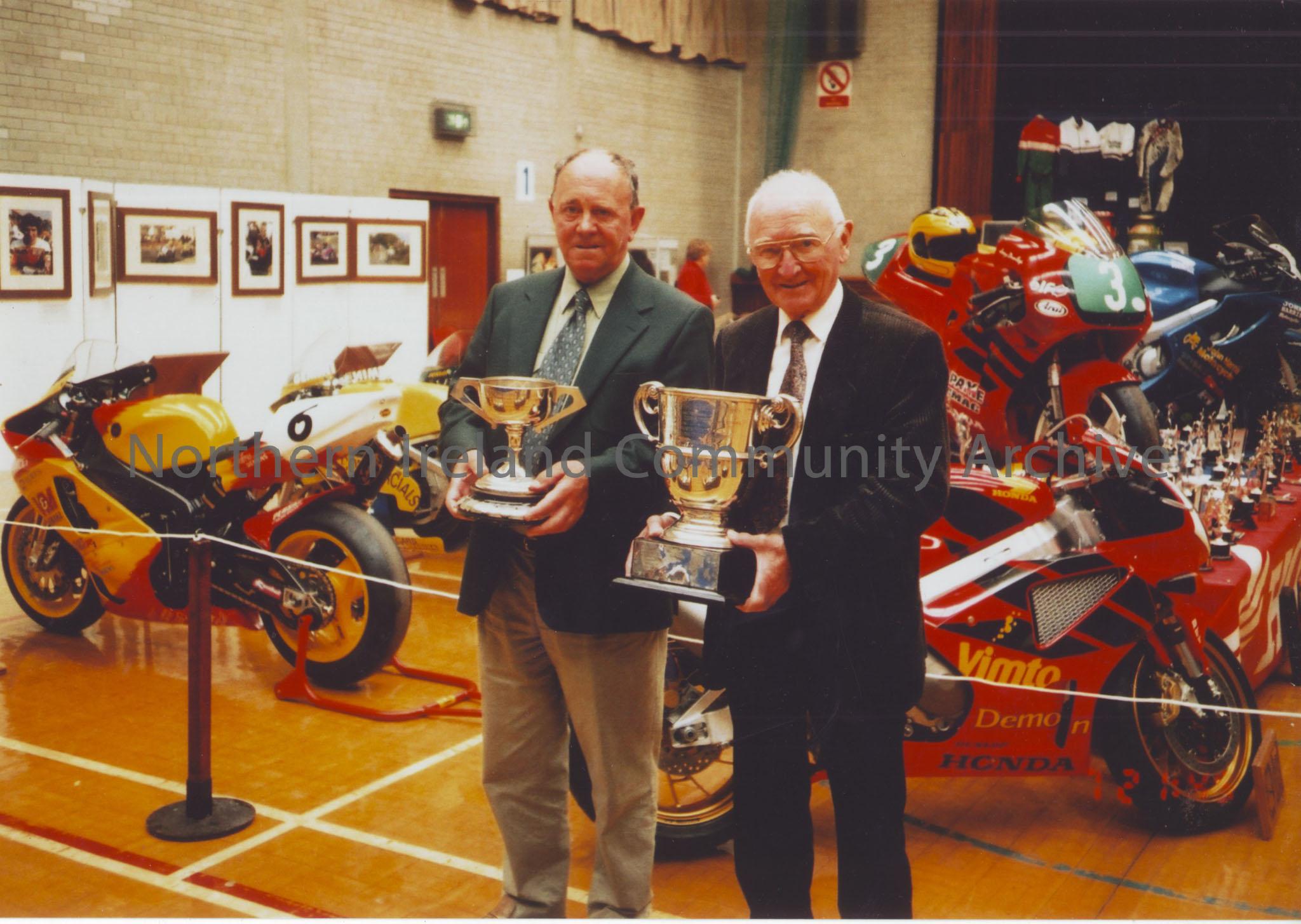 Photographs from Joey Dunlop exhibition May 2003. Photos include, Manxman Alan (W.A) Holmes (Dark Suit) with long time friend, local resident Jim McDe… – 2011.73 (2)