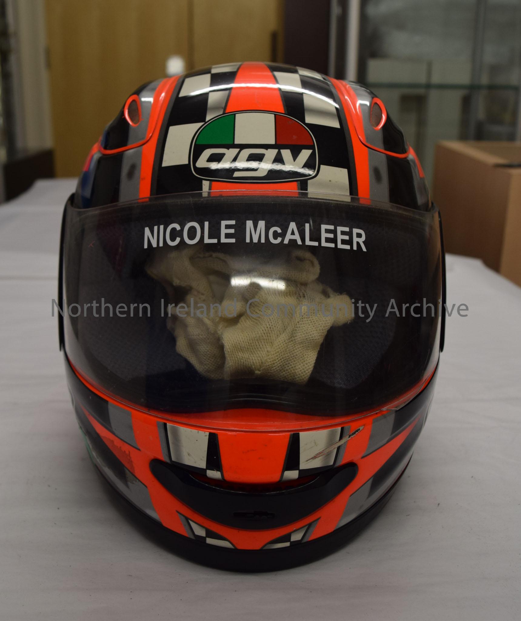 AGV Motorcycle helmet belonging to Nicole McAleer. Fluorescent orange with black and white check pattern on the top and grey and black down the side. – 2016.1 (2)