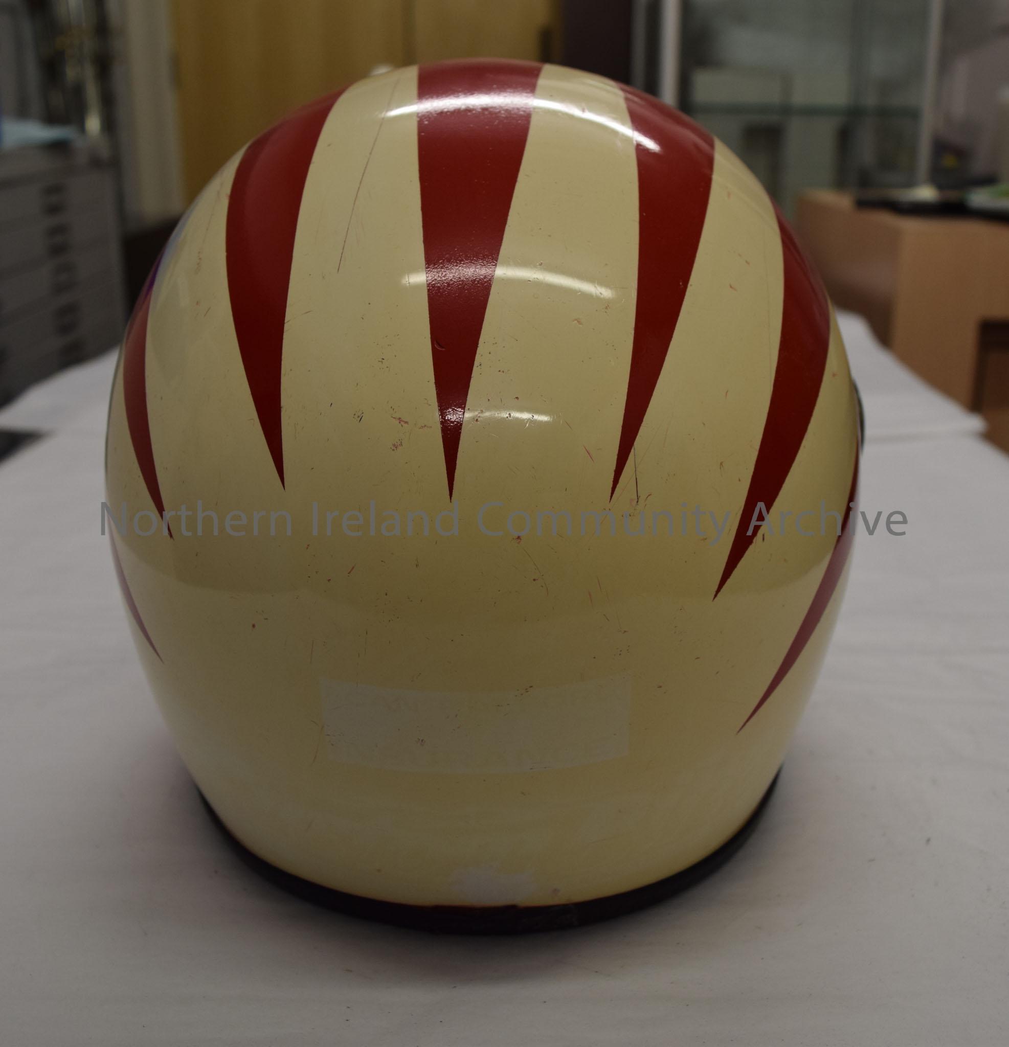 Motorcycle helmet signed by Ray McCullough. Cream with red pattern spreading back and the top of a green four leaved clover with a red hand in the cen… – 2016.101 (4)