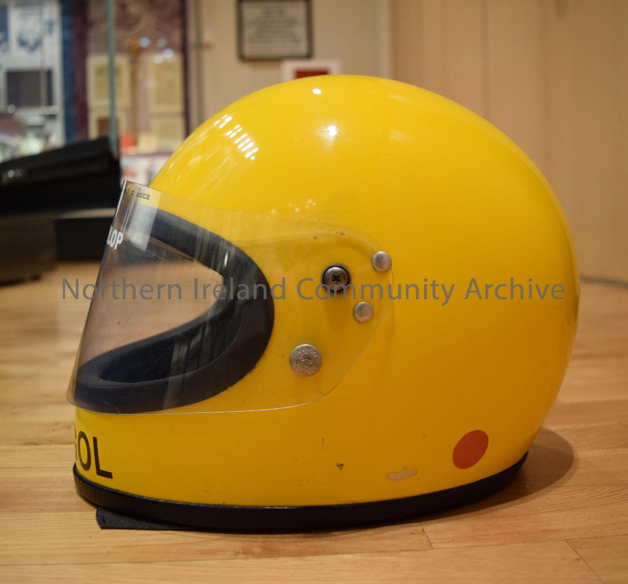 Kangol motorcycle helmet belonging to Joey Dunlop. Matt yellow helmet with a black strip down the middle. – 2016.106 (3)