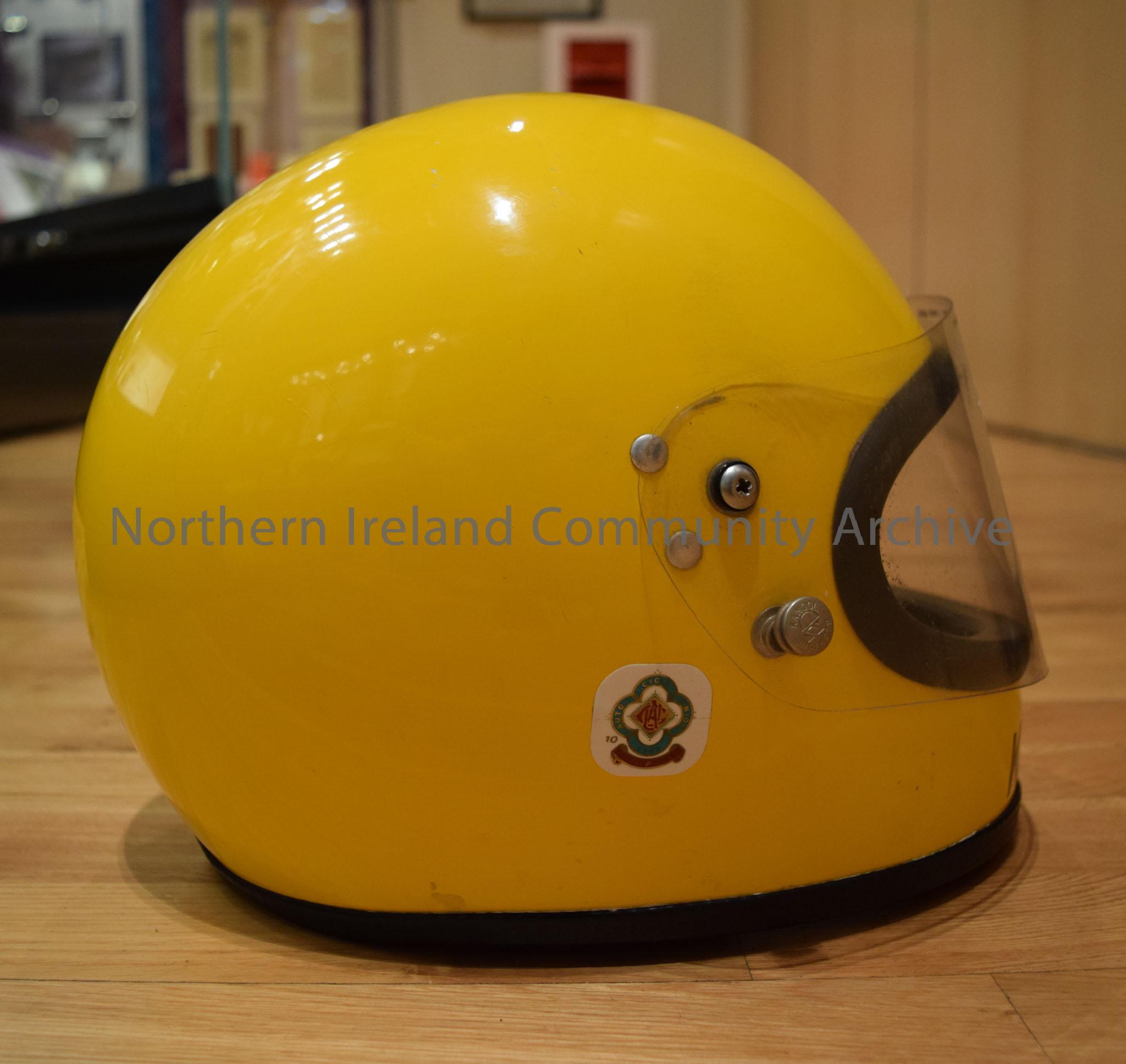 Kangol motorcycle helmet belonging to Joey Dunlop. Matt yellow helmet with a black strip down the middle. – 2016.106 (5)
