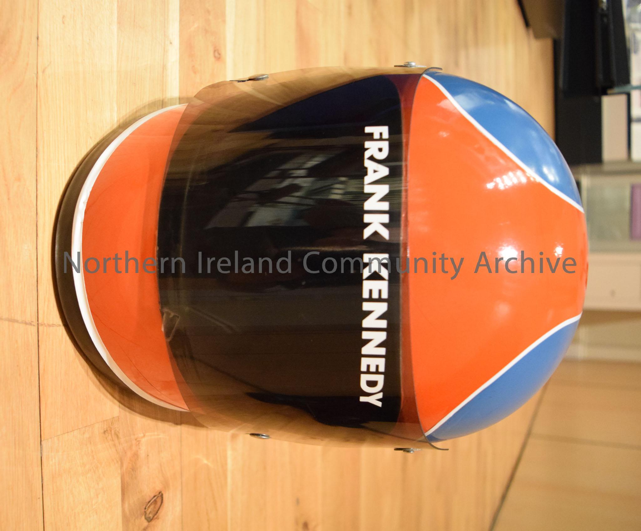 Shoei motorcycle helmet belonging to Frank Kennedy. Blue helmet with red front and red stripe down the middle with a white border- cracked – 2016.109 (2)