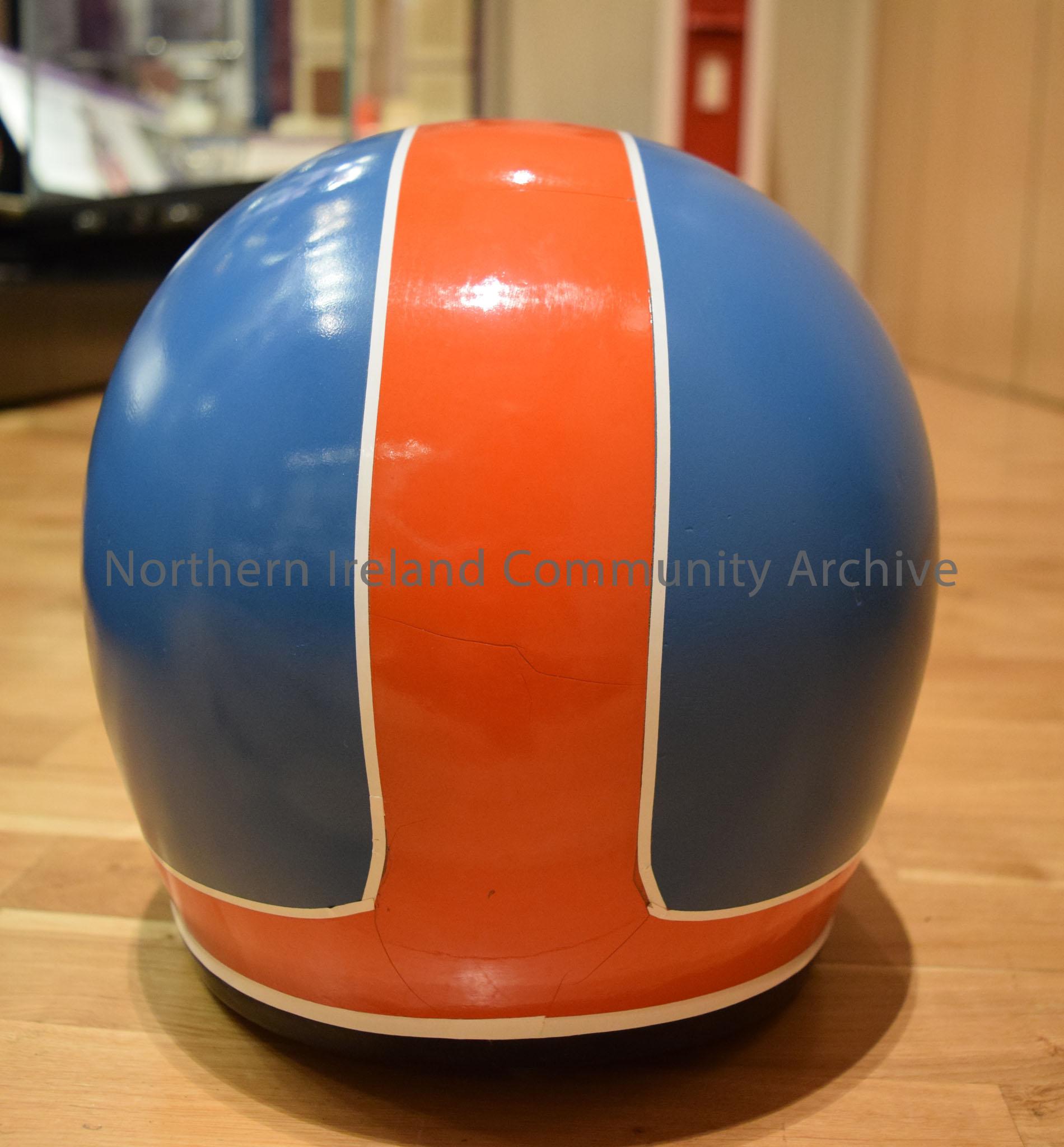 Shoei motorcycle helmet belonging to Frank Kennedy. Blue helmet with red front and red stripe down the middle with a white border- cracked – 2016.109 (4)