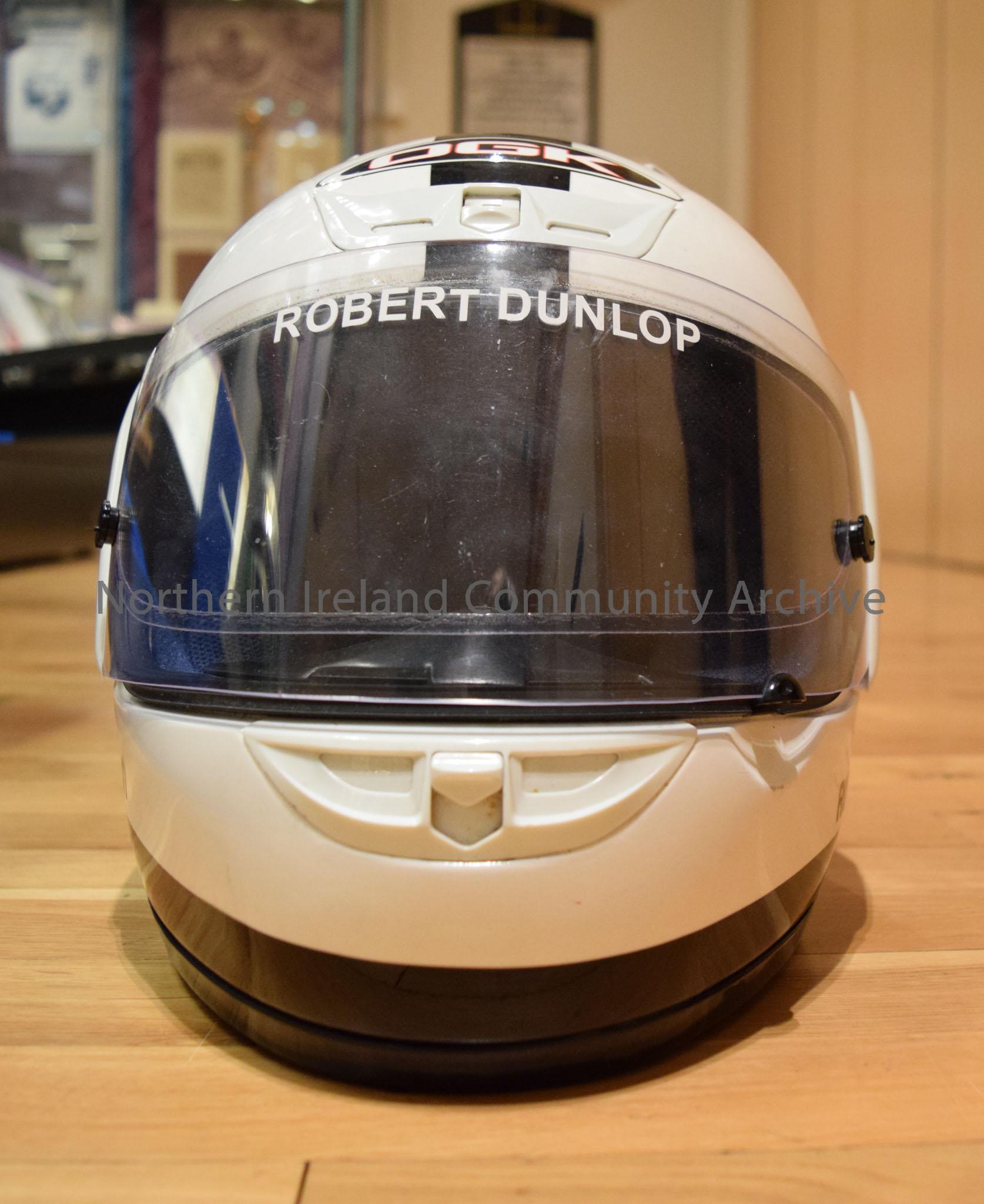 OGK motorcycle helmet belonging to Robert Dunlop. White helmet with a black stripe down the middle and black tear-drop shape on each side. – 2016.111 (2)
