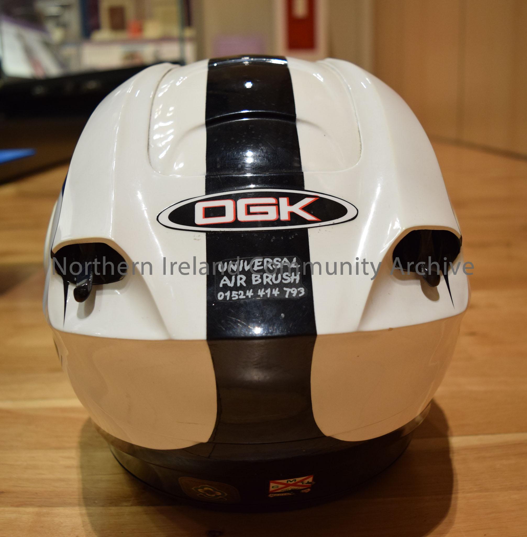 OGK motorcycle helmet belonging to Robert Dunlop. White helmet with a black stripe down the middle and black tear-drop shape on each side. – 2016.111 (4)