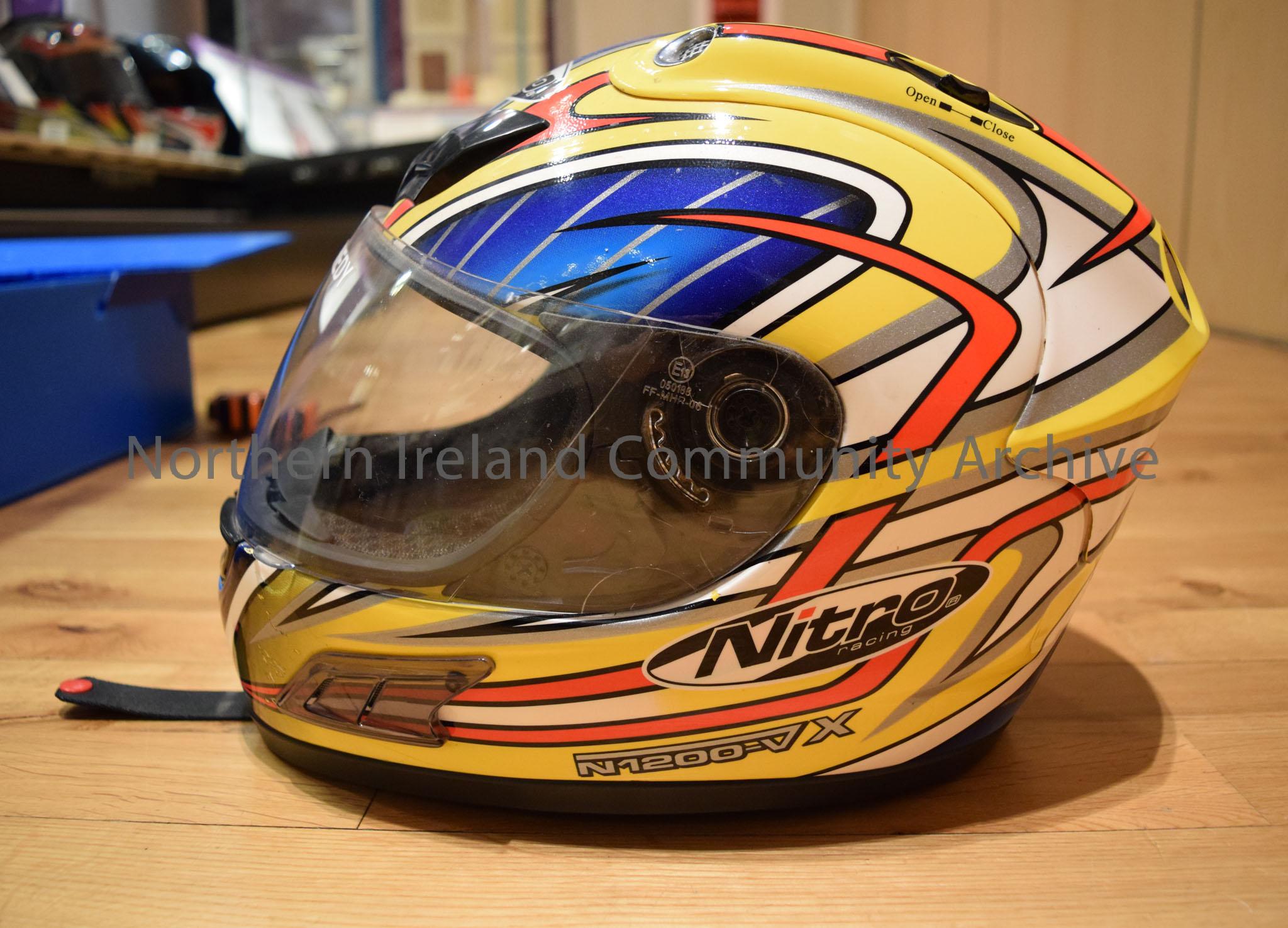 Nitro Racing motorcycle helmet belonging to Frank Kennedy. Yellow helmet with white, red and grey detail and dark blue and grey stripe pattern in the … – 2016.113 (3)