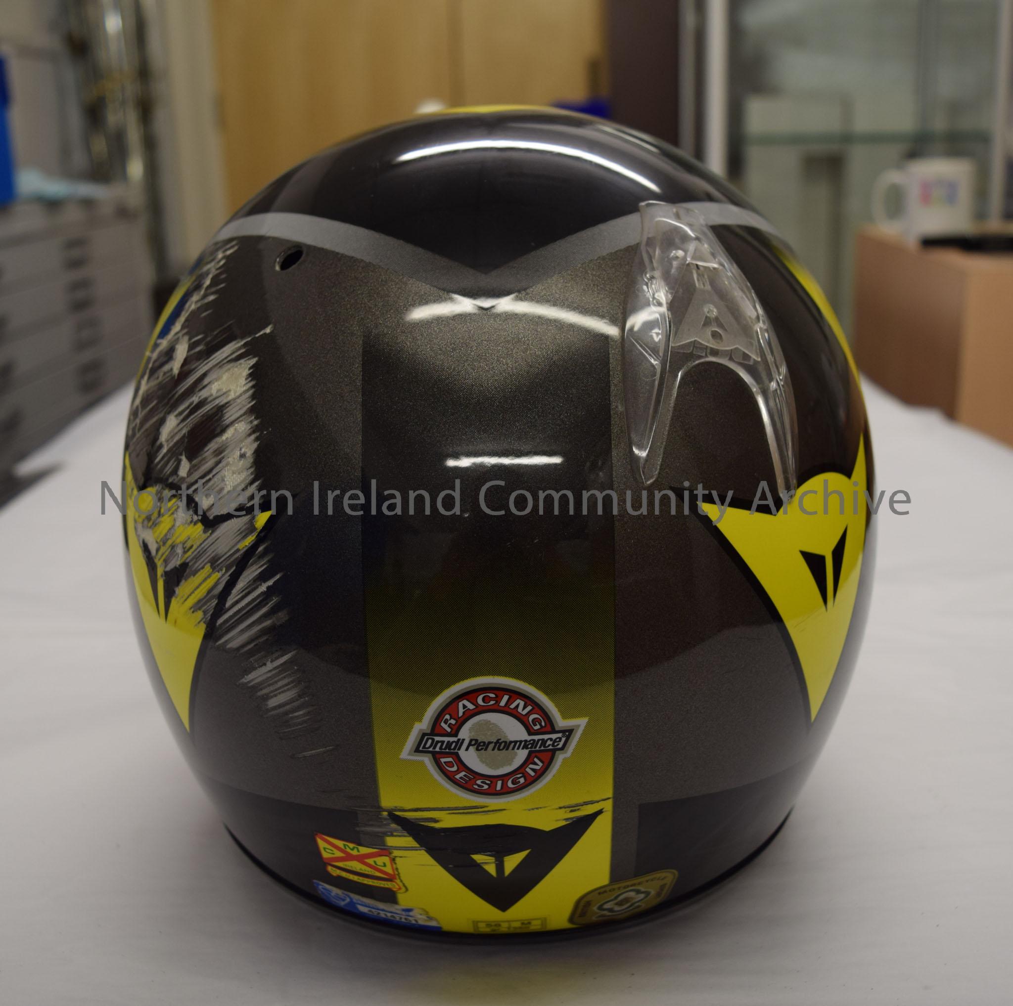 Dainese motorcycle helmet belonging to Raymond Hodge. Black, silver and yellow helmet with black visor and triangular shaped logo on the front. – 2016.12 (4)