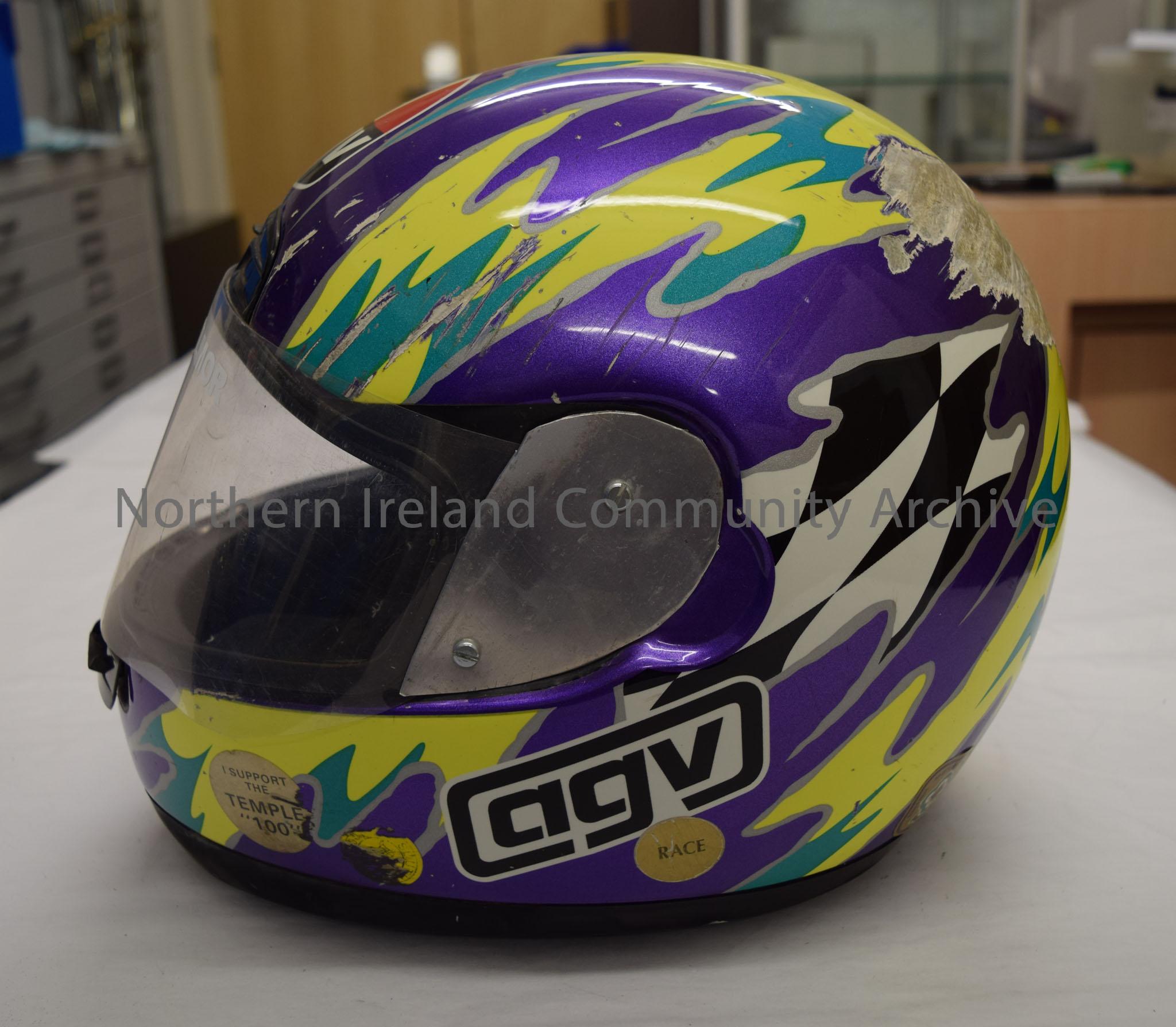 AGV motorcycle helmet belonging to Victor Gilmore. Purple with green and yellow pattern throughout and small section of black and white chequered patt… – 2016.53 (3)