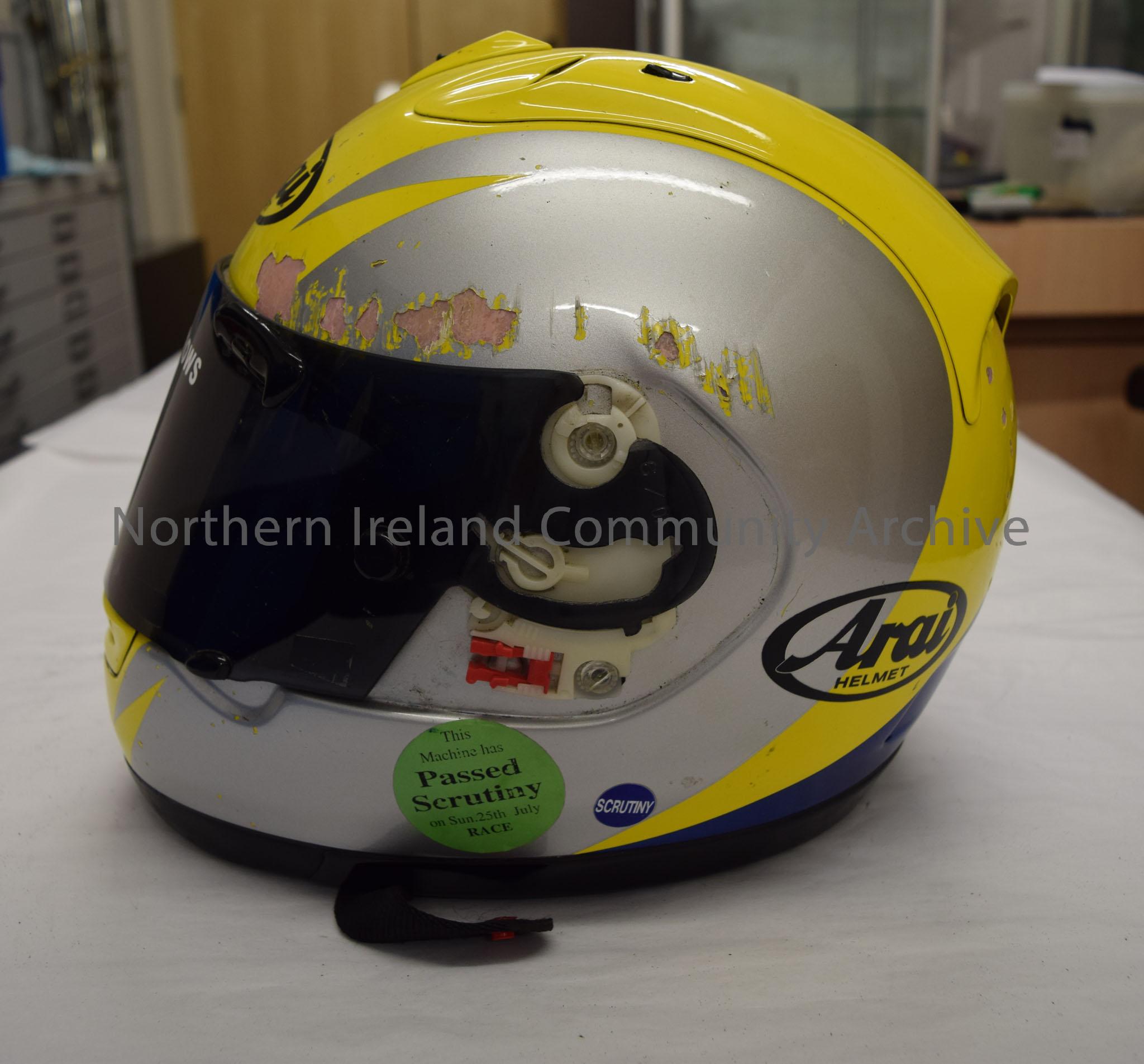 Arai motorcycle helmet belonging to John Burrows. Yellow helmet with silver sides and a blue stripe running from the middle of the top to the bottom a… – 2016.59 (3)