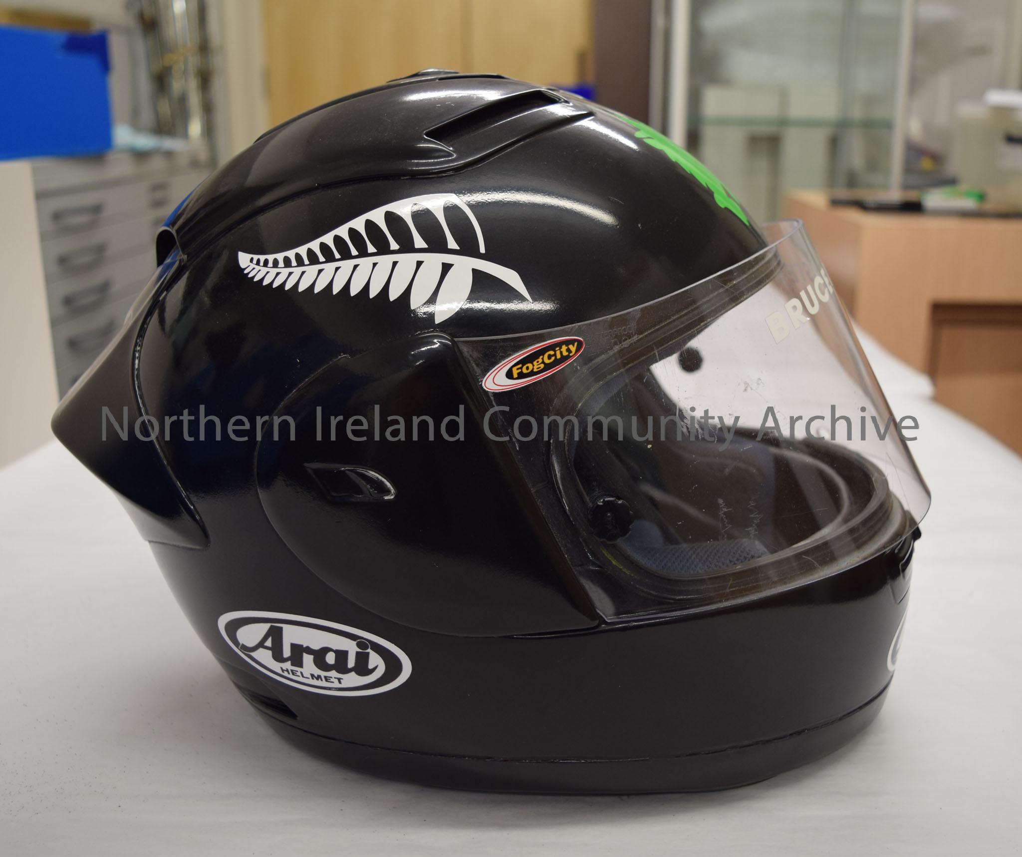 Arai motorcycle helmet belonging to Bruce Anstey. Plain black helmet with an image of a black and white fern leaf on each side and a green silhouette … – 2016.72 (5)