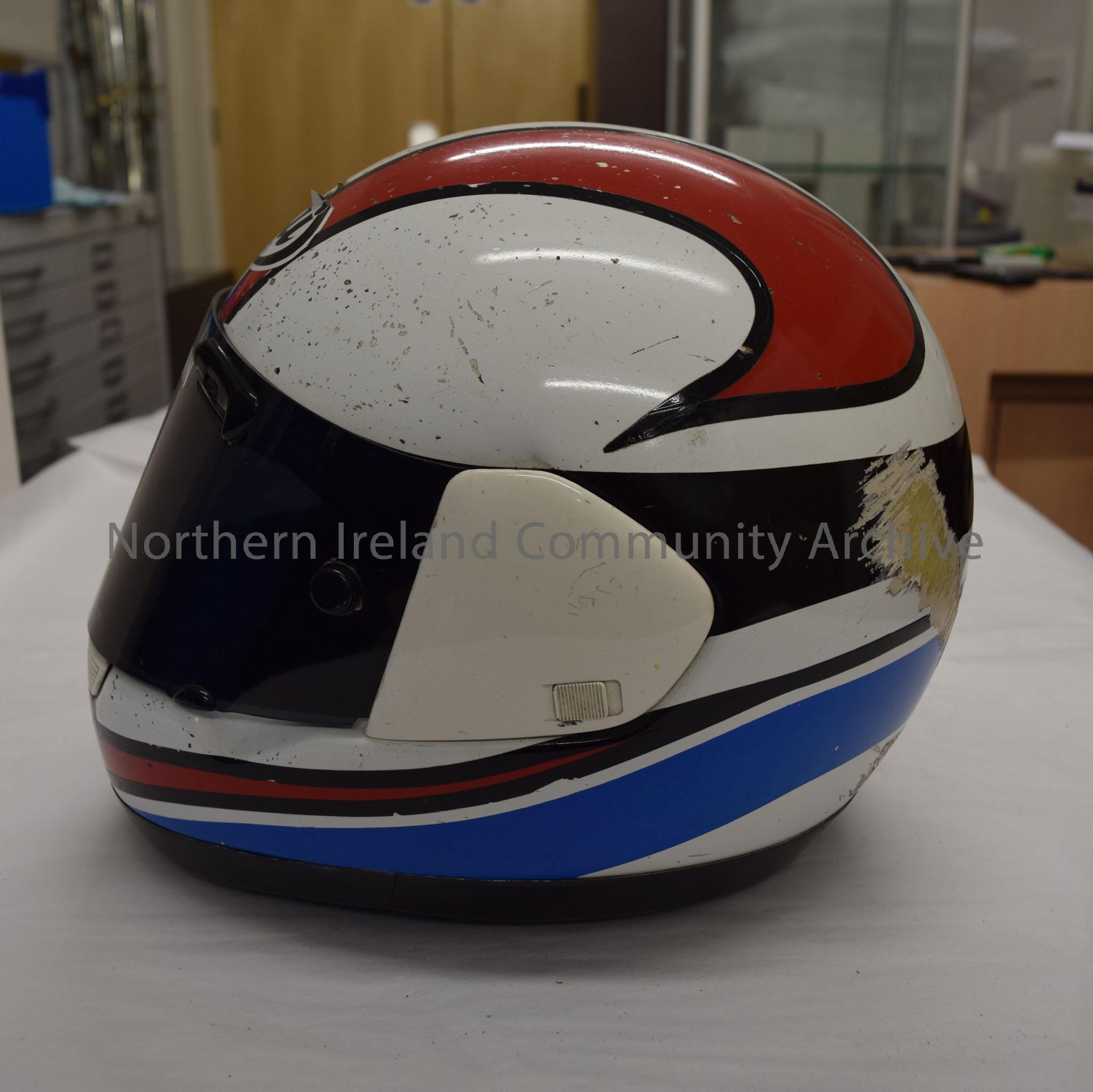 Arai motorcycle helmet belonging to Mike Swann. White helmet with red pattern on top and black stripe around the middle and blue pattern at the back. – 2016.80 (3)