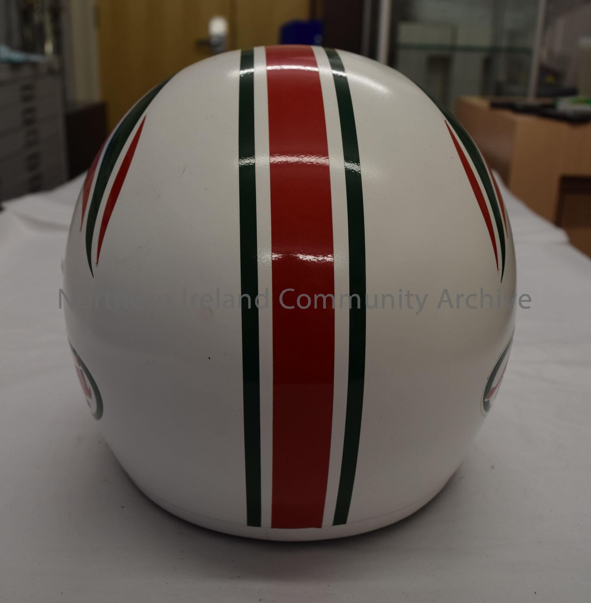 Arai motorcycle helmet belonging to Owen McNally. White helmet with red and green stripes down the middle and a red and green pattern on the sides. – 2016.82 (4)