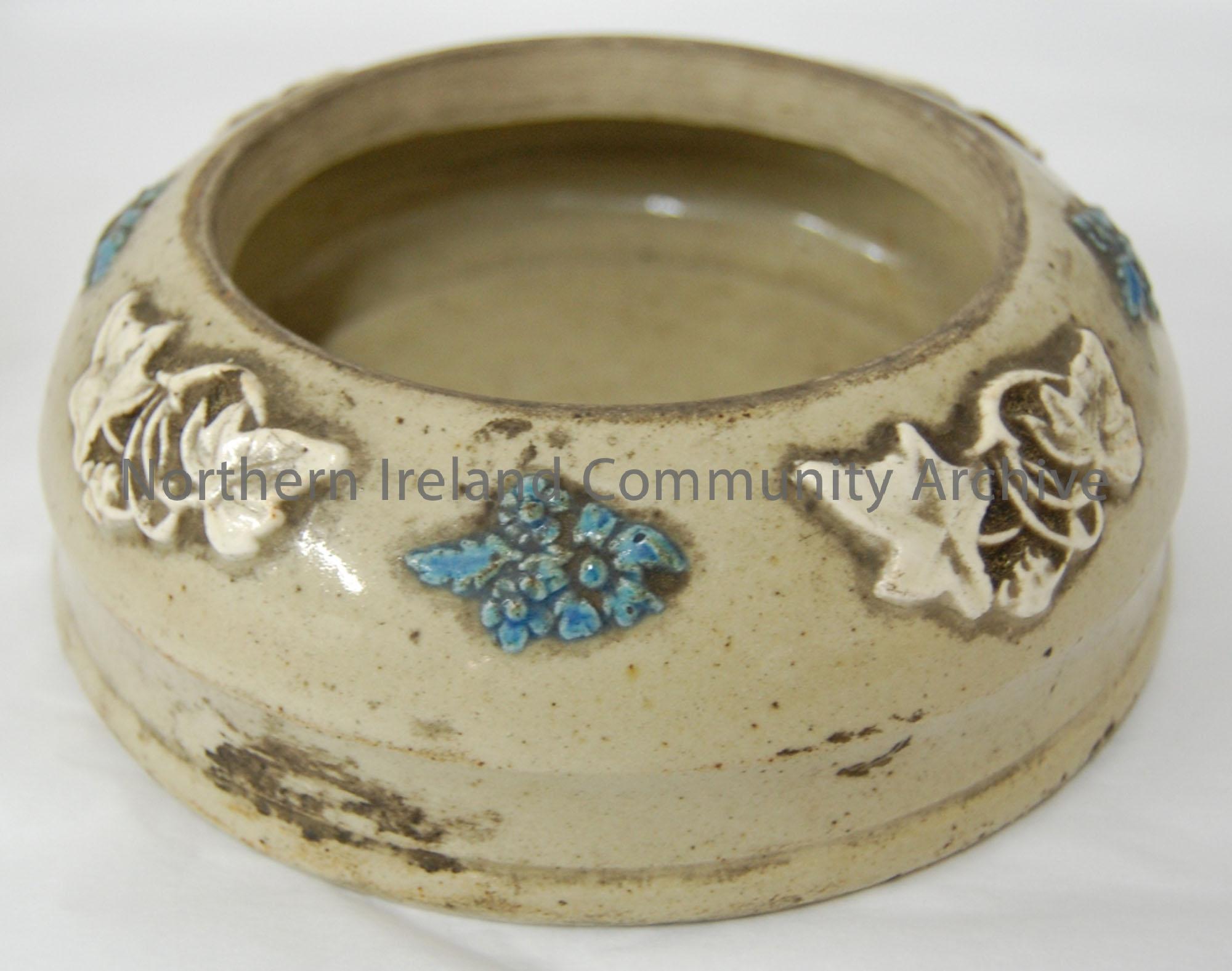 Light brown glazed bowl decorated with embossed blue and white flowers.