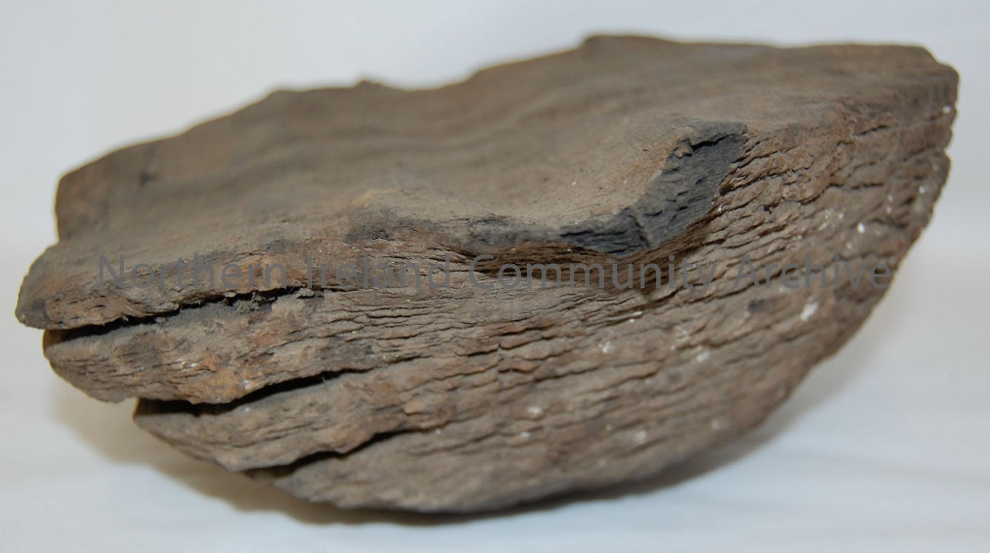 Dome shaped piece of wood with flat base and concentric grooves evident.