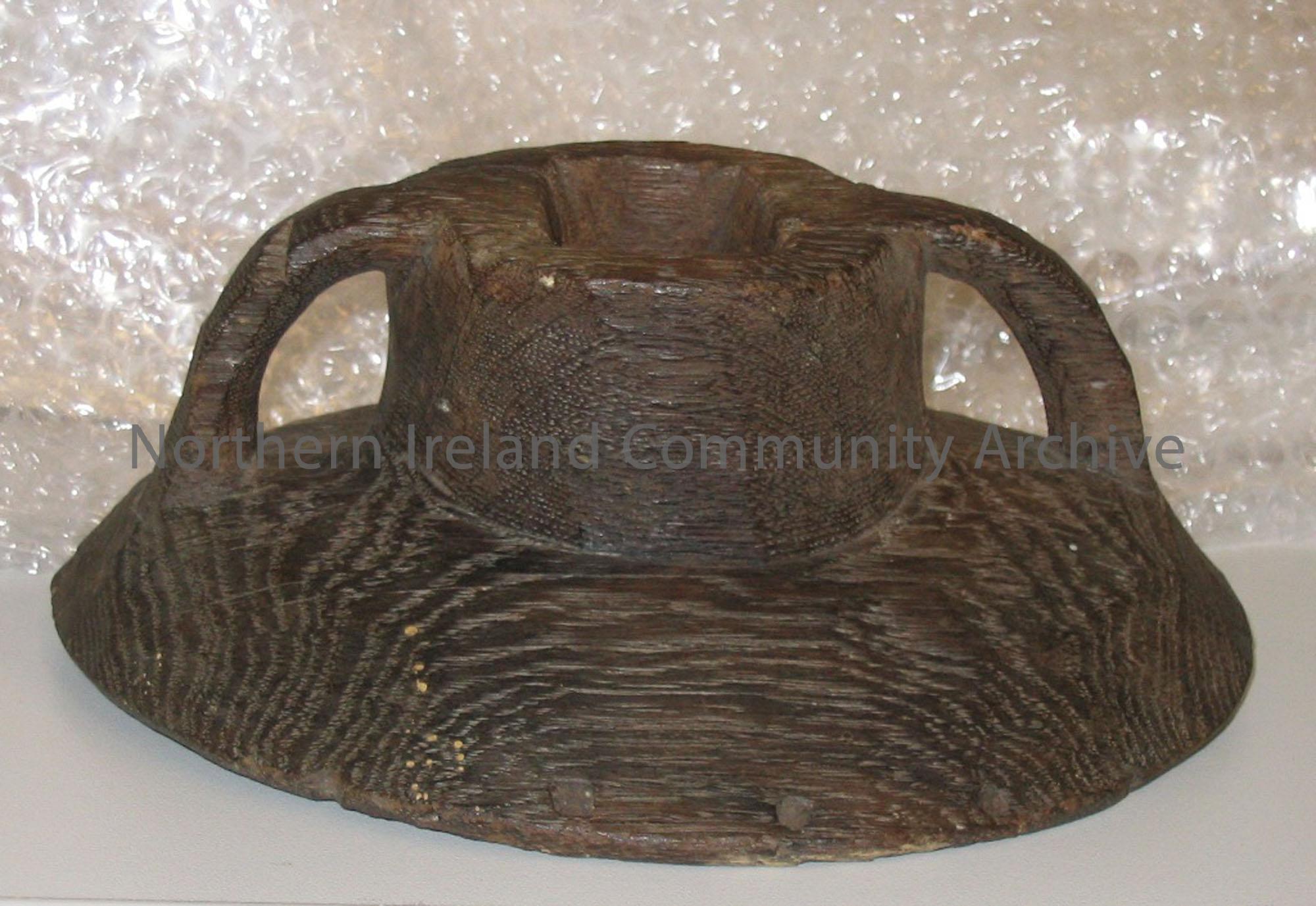 Vessel lid. Circular base with round neck and two handles joined to base and neck.There is a square hole pierced through the neck and base.