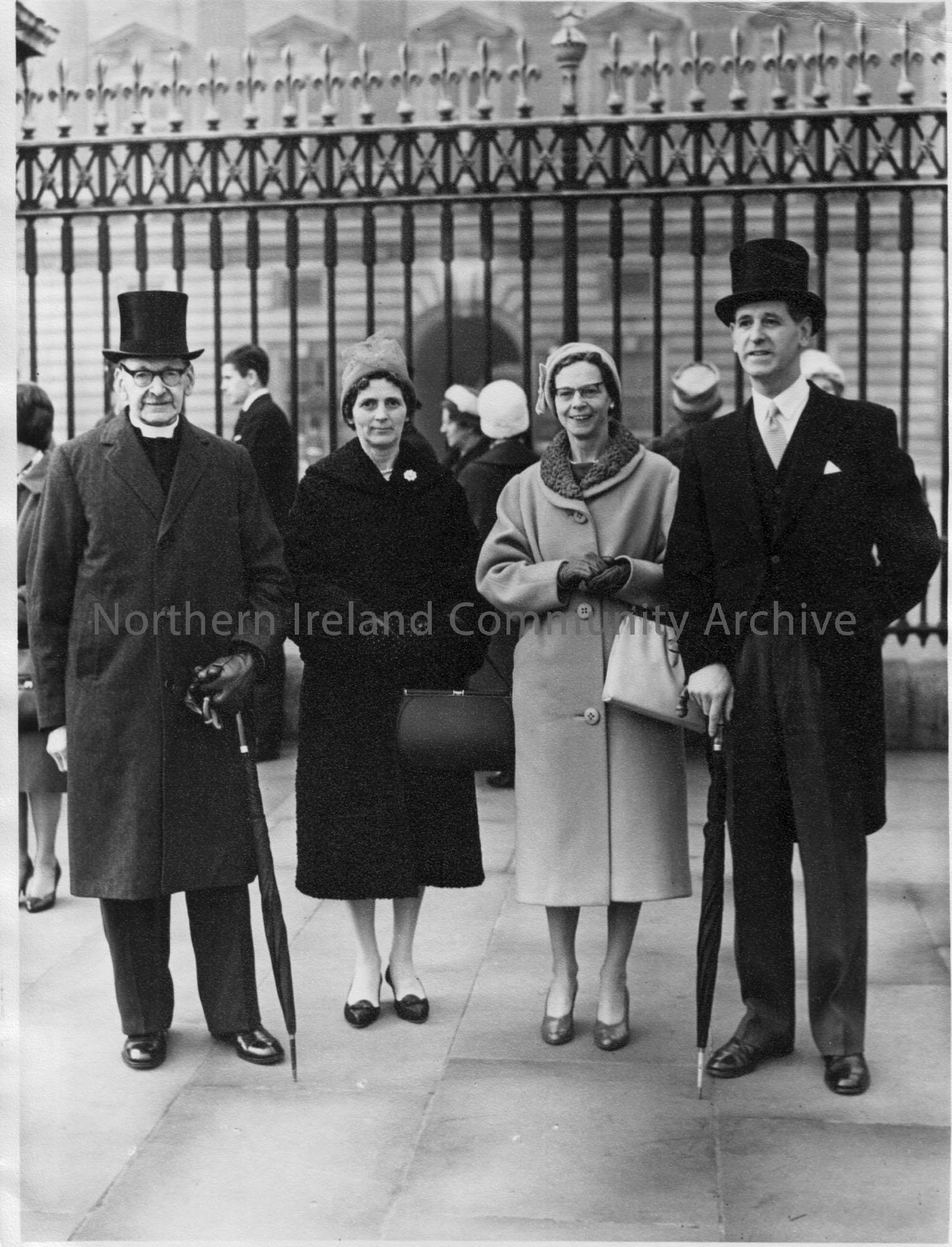 Rev.R.J. McIlmoyle standing outside Buckingham Palace on the occassion of receiving his OBE. A man and two women are also in the photograph