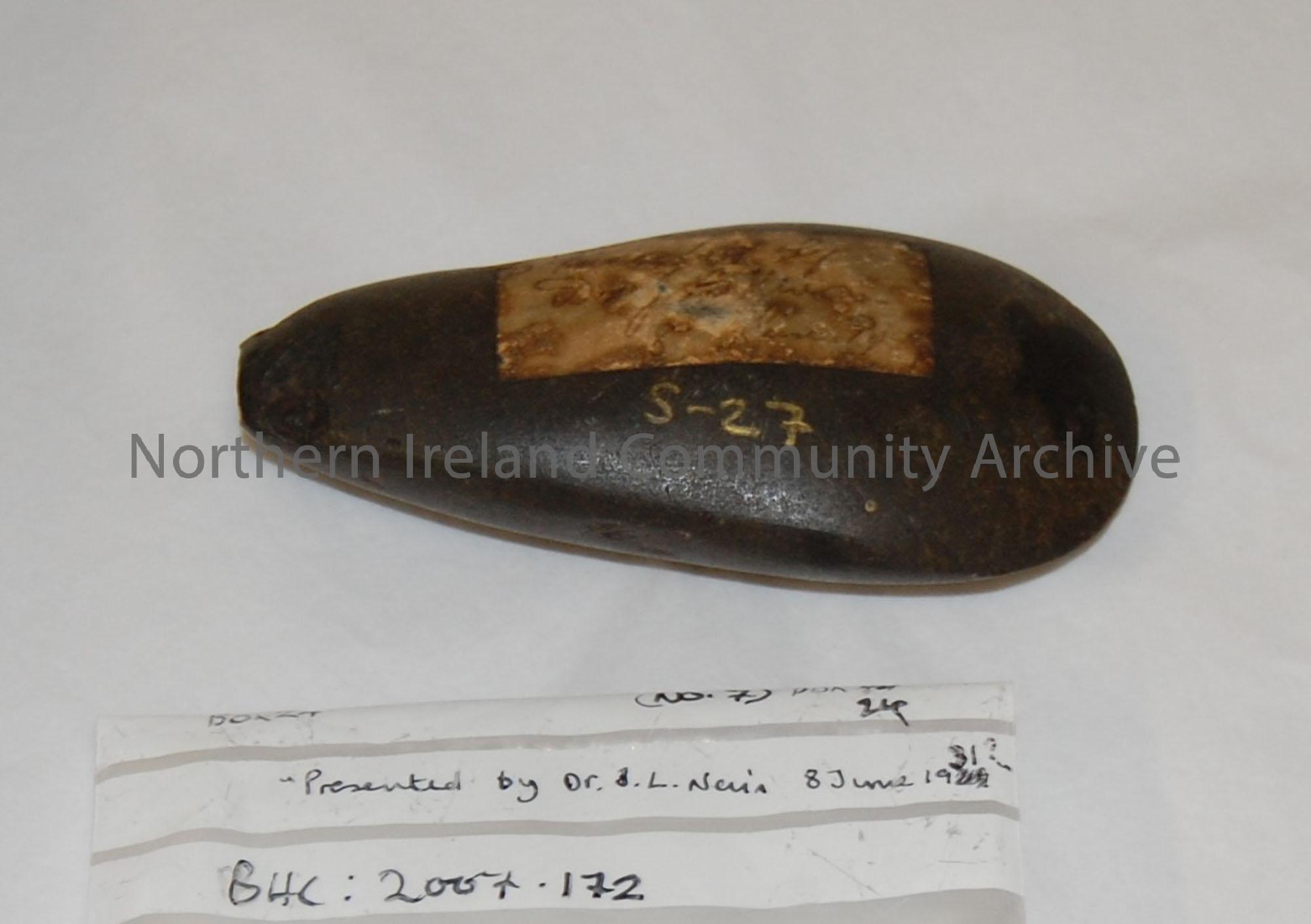 Polished stone axe, Stone Age. Label stuck on side reads, ‘Presented by Dr. J.L. Nevin..’