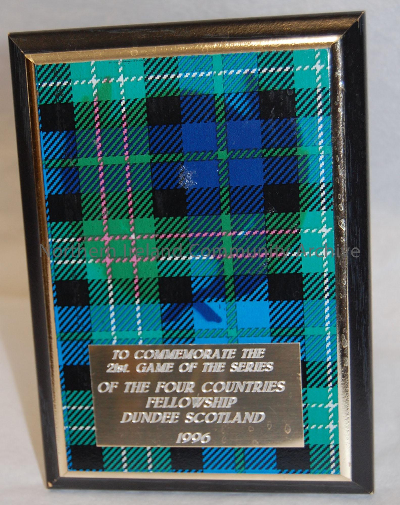 Rectangle shaped plaque with a green tartan pattern ‘To commemorate the 21st Game of the Series of the Four Countries Fellowship Dundee Scotland 1996.