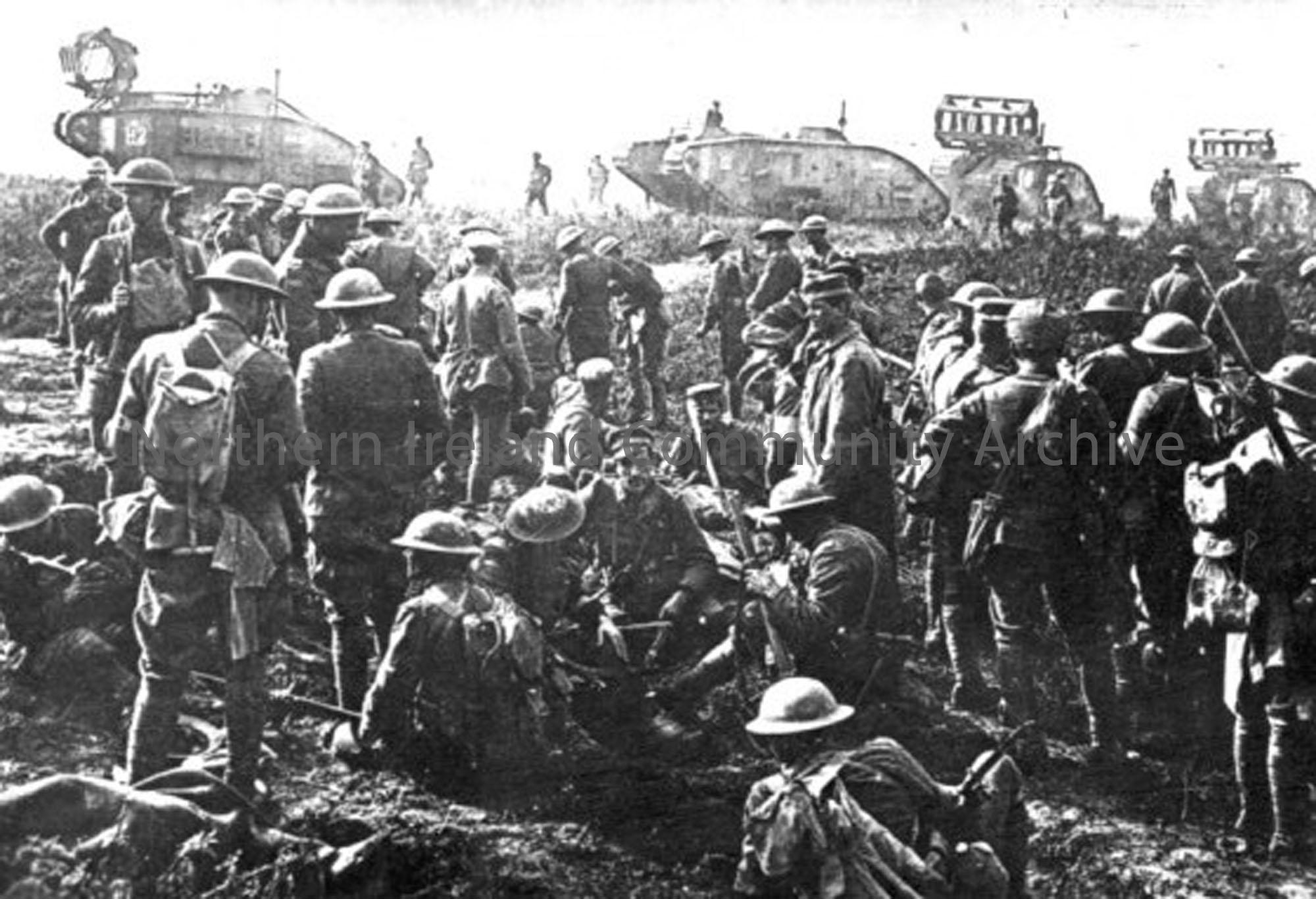 A crowd of German prisoners are escorted by British troops. In the background a column of tanks move to the front line. On the front of three of the t…