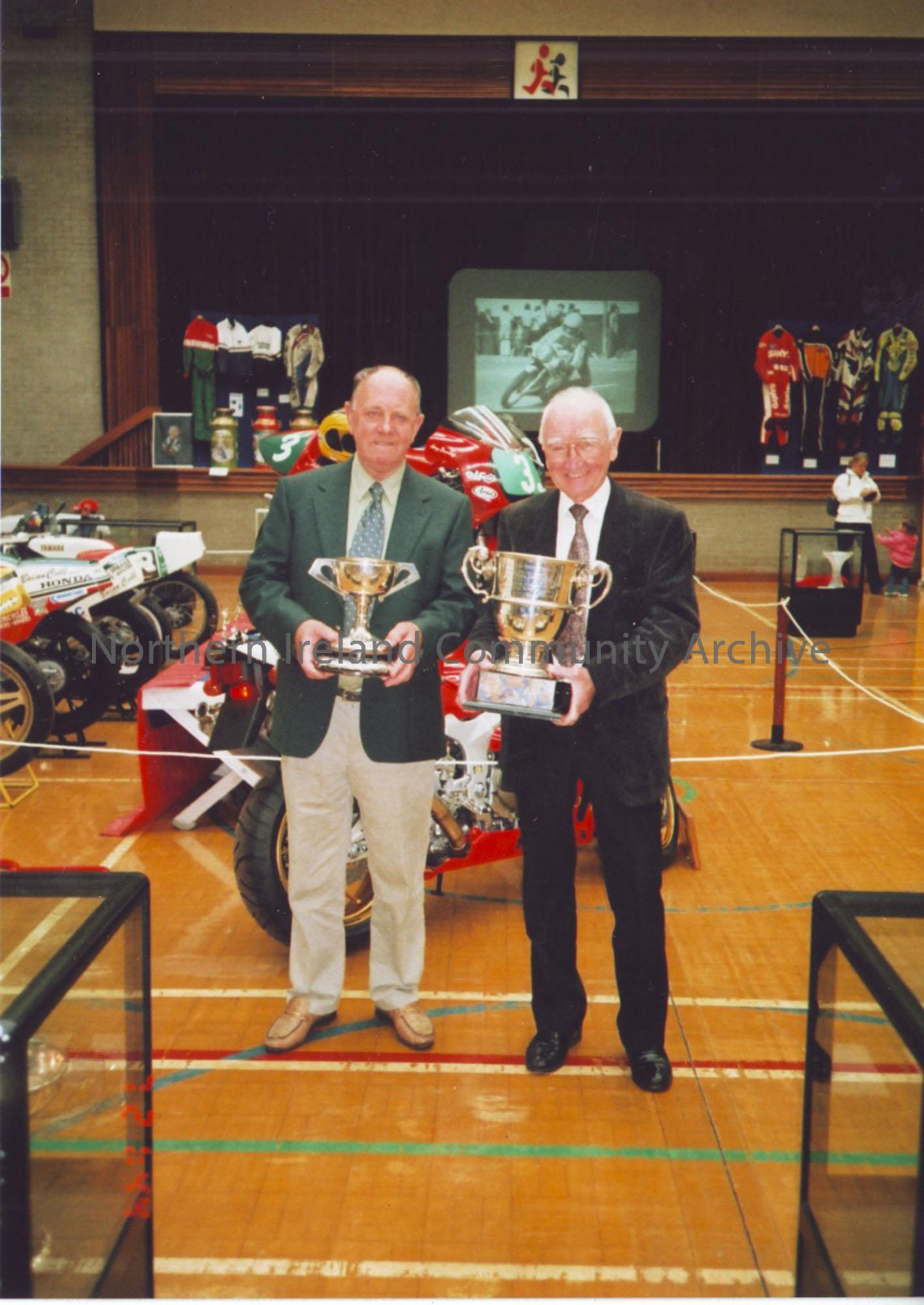 Photographs from Joey Dunlop exhibition May 2003. Photos include, Manxman Alan (W.A) Holmes (Dark Suit) with long time friend, local resident Jim McDe…
