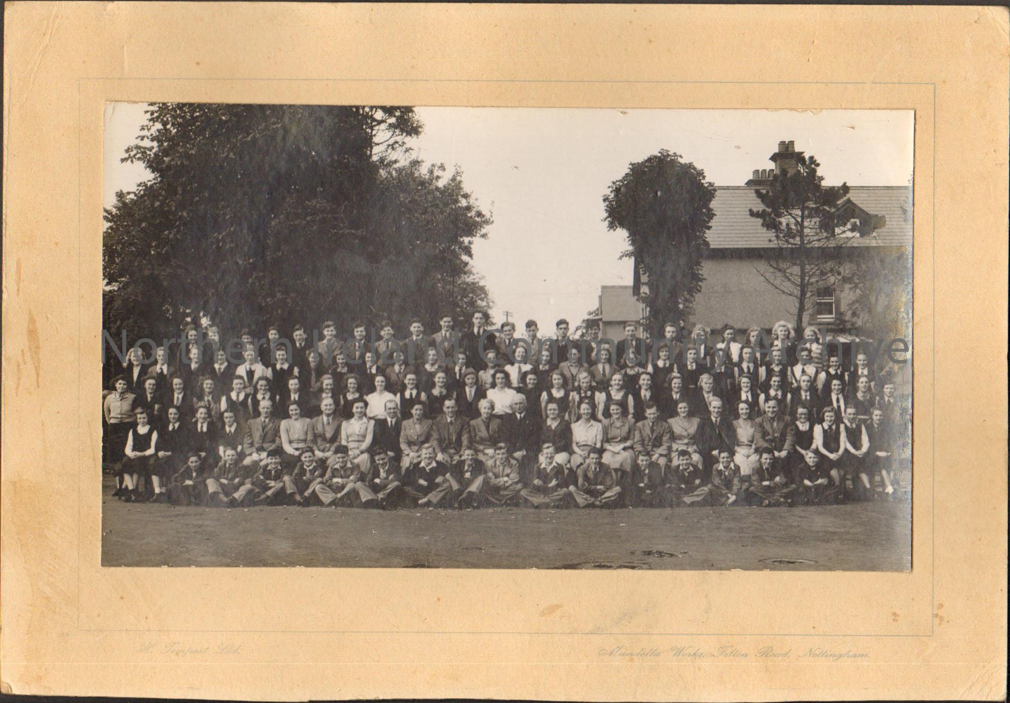 Black and white photograph of pupils and teachers from Ballymoney Technical School. Mounted on brown cardboard