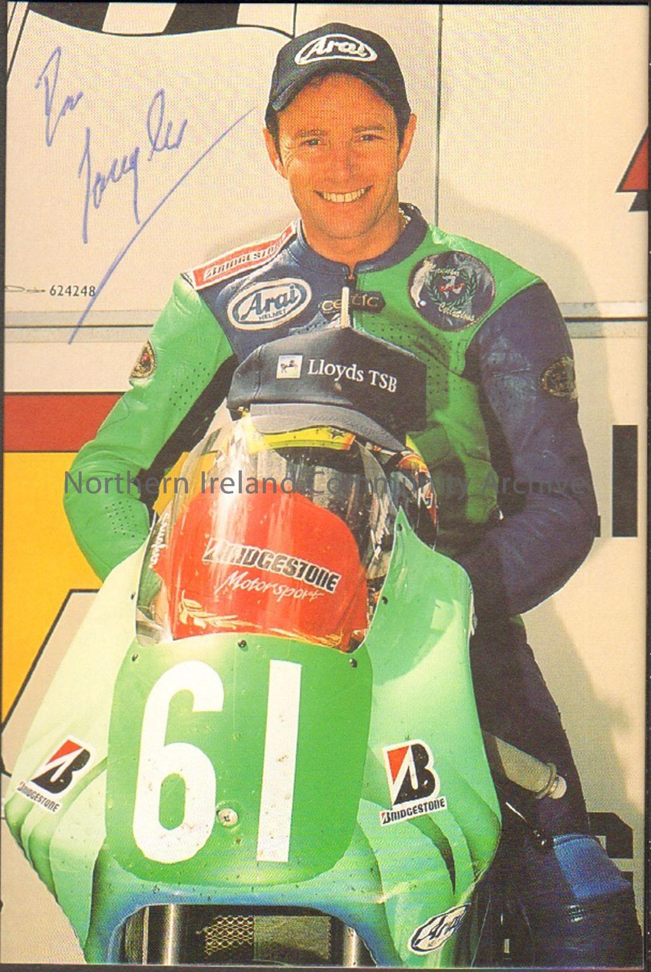 Signed photograph of Ian Lougher sitting on a green motorbike with number 61 on the front wearing green and blue leathers and no helmet.