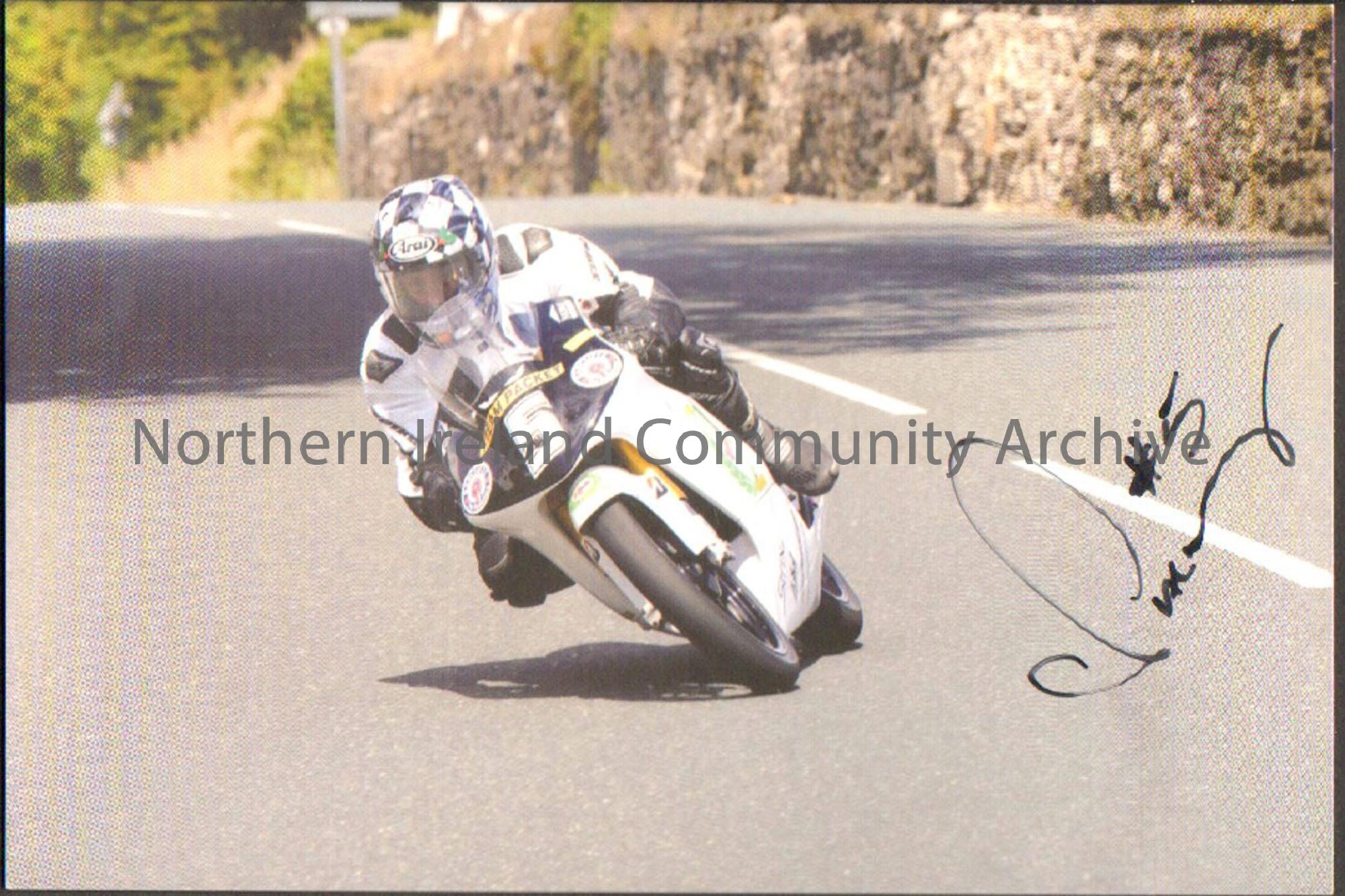 Signed photograph of Chris Palmer riding a black and white motorbike with number 5 on the front and wearing black and white leathers on a wide road wi…