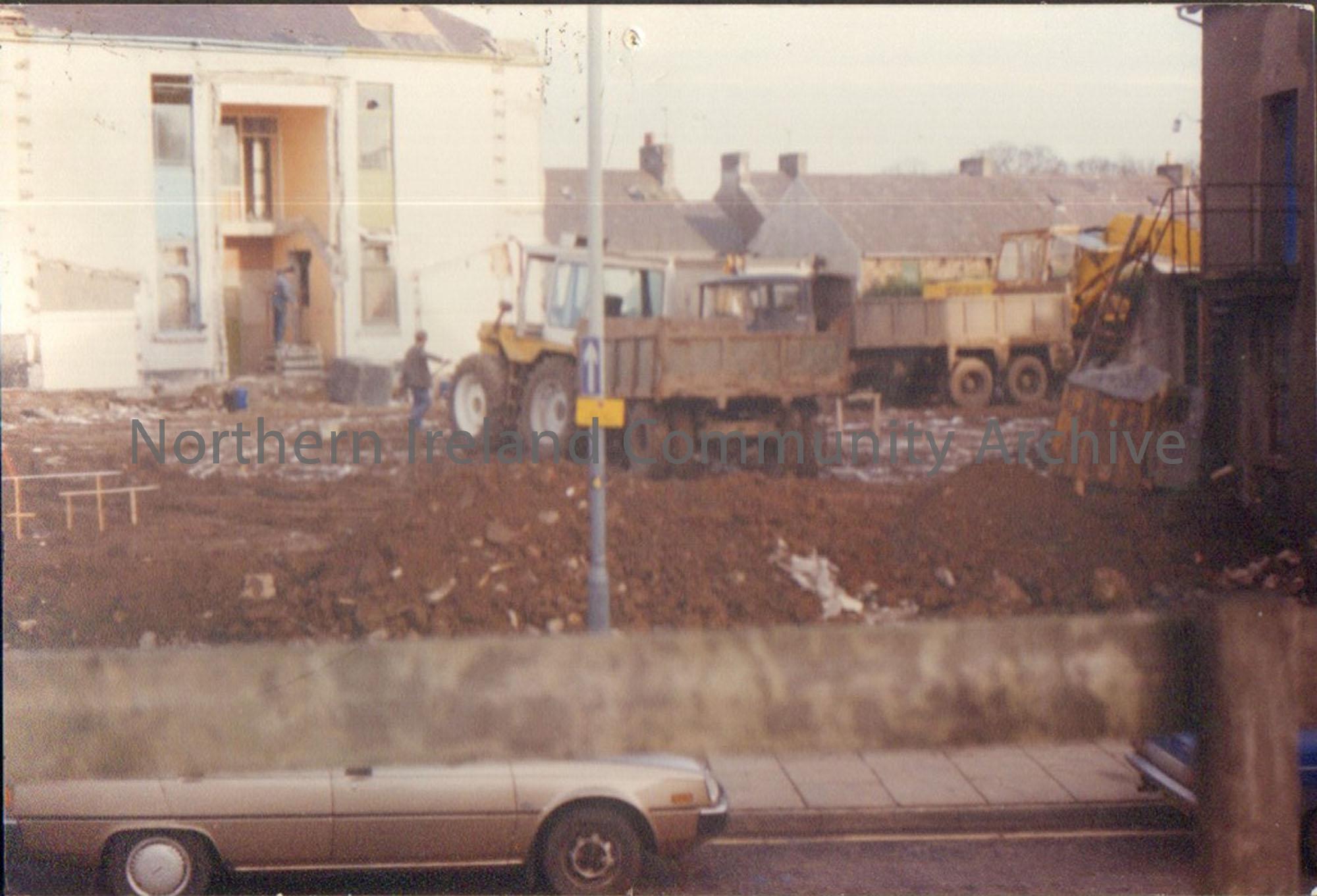 Colour photograph of the building of Riada House Extension. Building site with yellow tractor and trailer in the centre and silver car parked at the b…