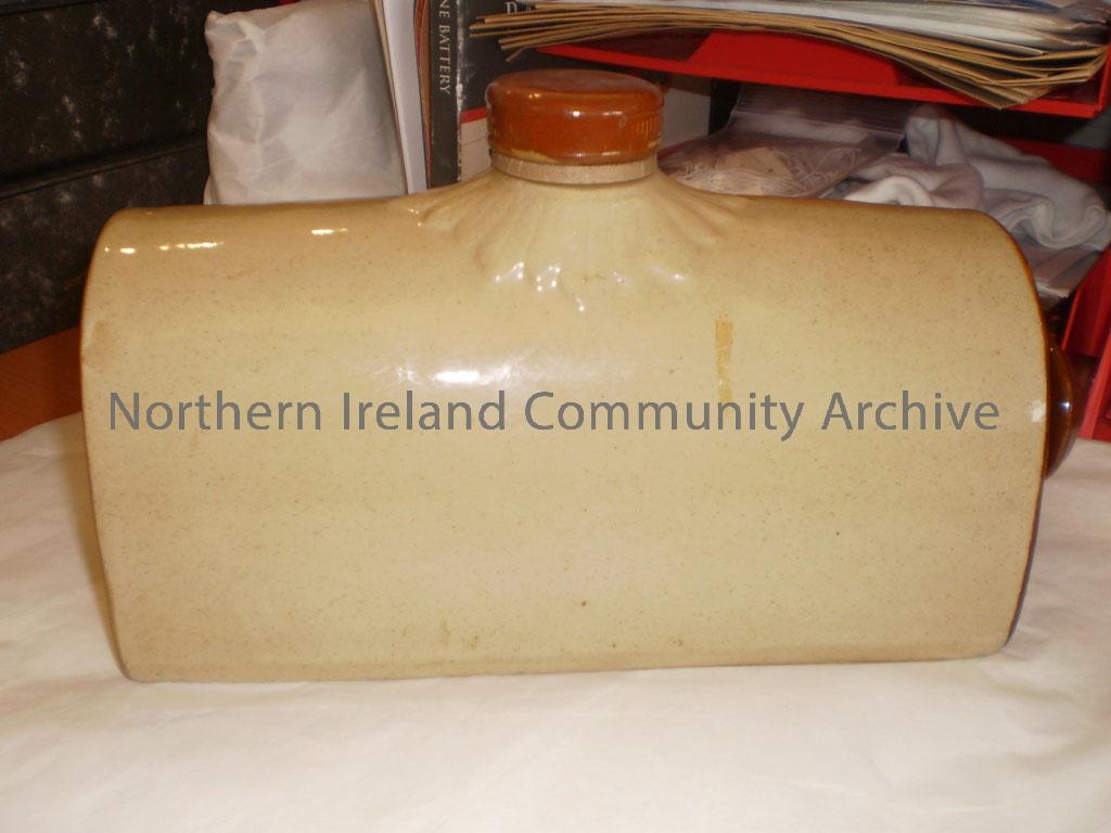 Cream coloured ceramic hot water bottle with a brown lid