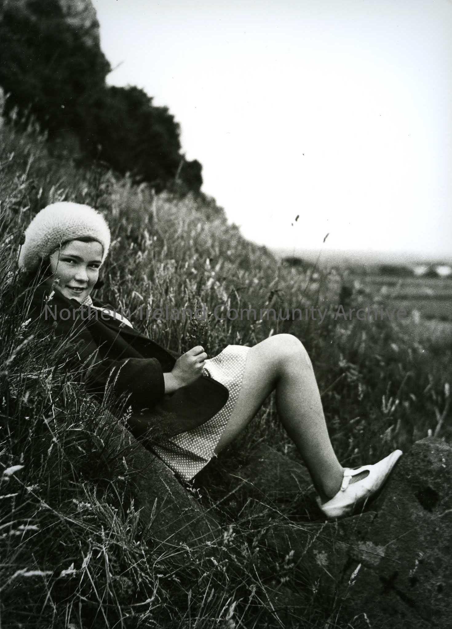 Printed black and white photograph – Olive Craig (nee Henry) sitting on a grassy hill.