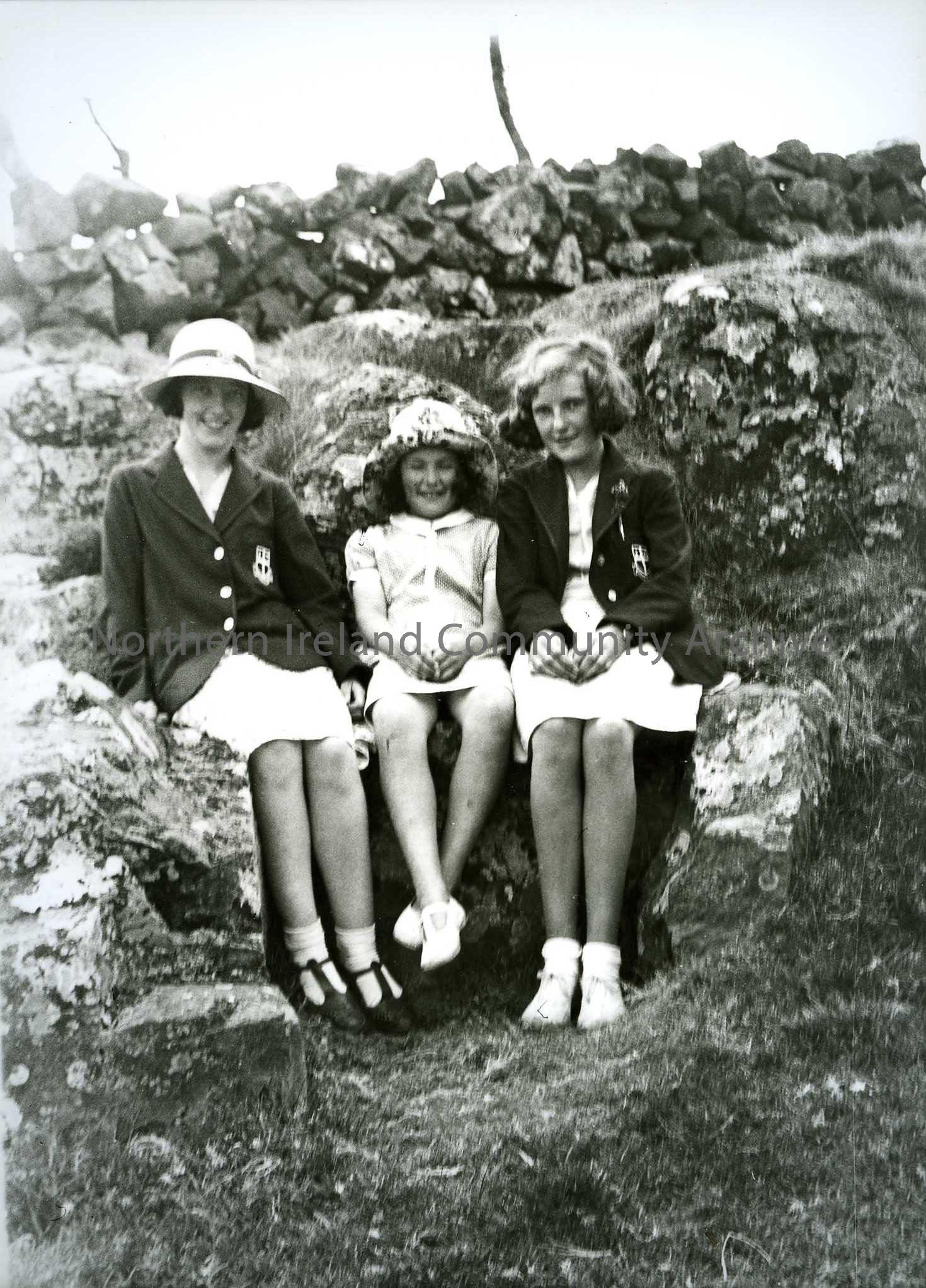 Printed black and white photograph – Olive Craig (nee Henry, Sam Henry’s daughter) sits in the middle of two girls in Coleraine High School blazers on…
