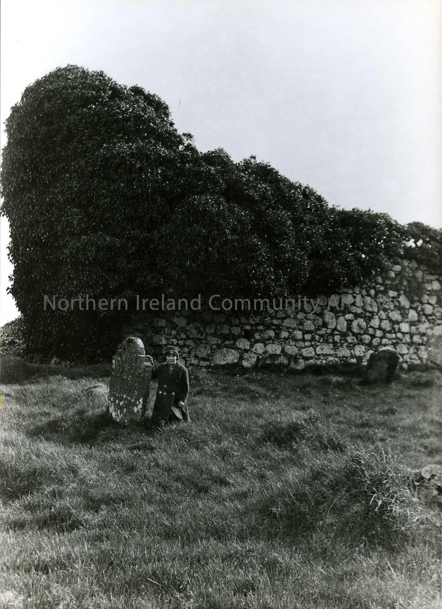 Printed black and white photograph – Church ruin? Olive Craig (nee Henry, Sam’s daughter) sits beside a gravestone.