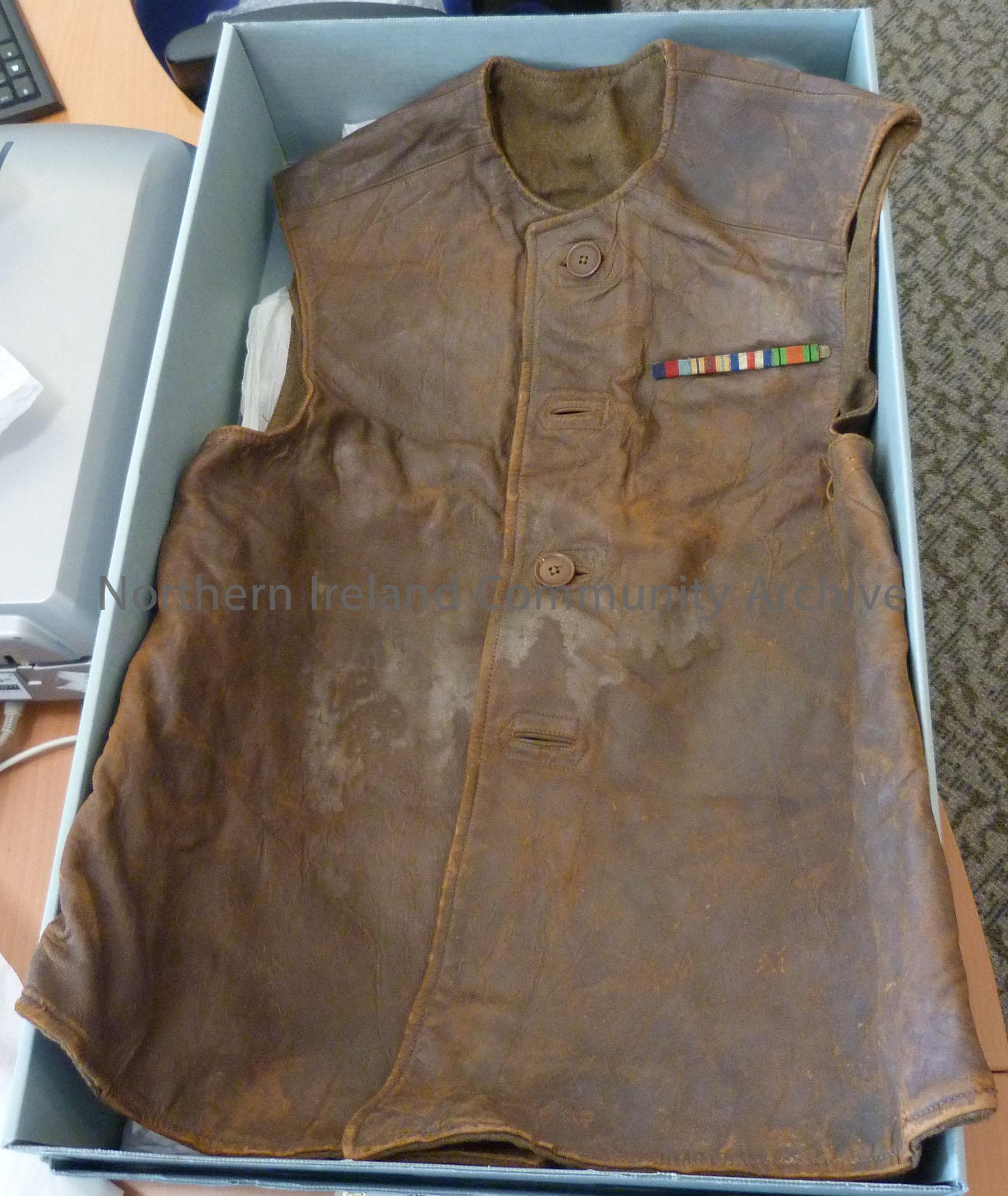 Brown leather sleeveless jacket with four buttons down the front and a multicoloured medal bar on left breast