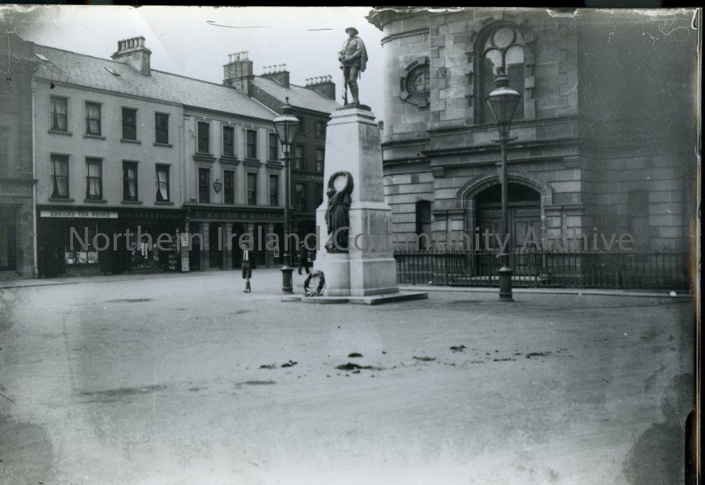 Black and White photograph of the War memorial, The Diamond, Coleraine 1929/1930.  A young boy is walking beside the memorial.  The Town Hall is situated behind the memorial. (3205)