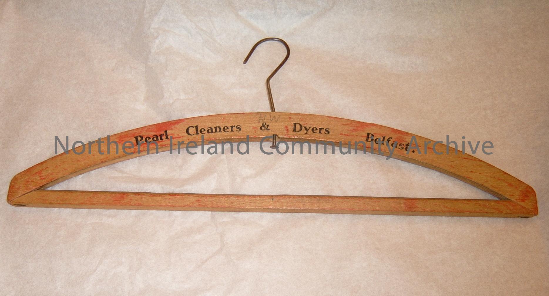 wooden clothes hanger with wire hook. Printed onto the hanger is Pearl Cleaners & Dyers Belfast. written in pencil on the hanger are the letters NW. (This firm had laundry collection and delivry to your door weekly by van) (3852)