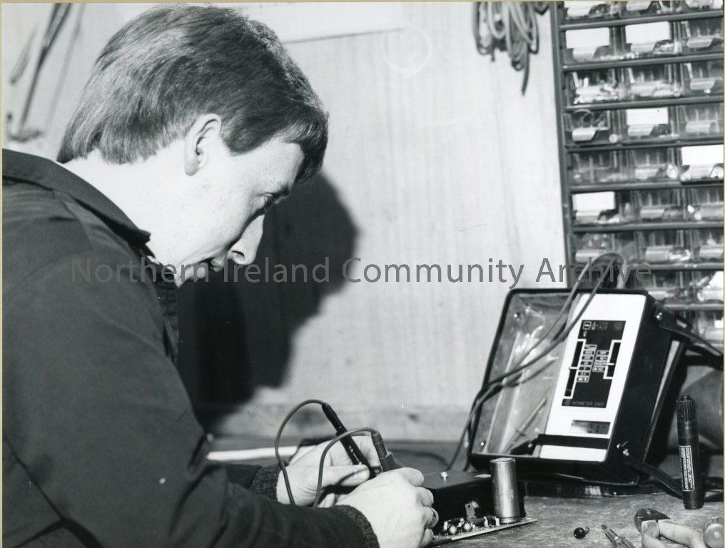 black and white photograph of a man in a workshop testing electrial equipment  (3804)