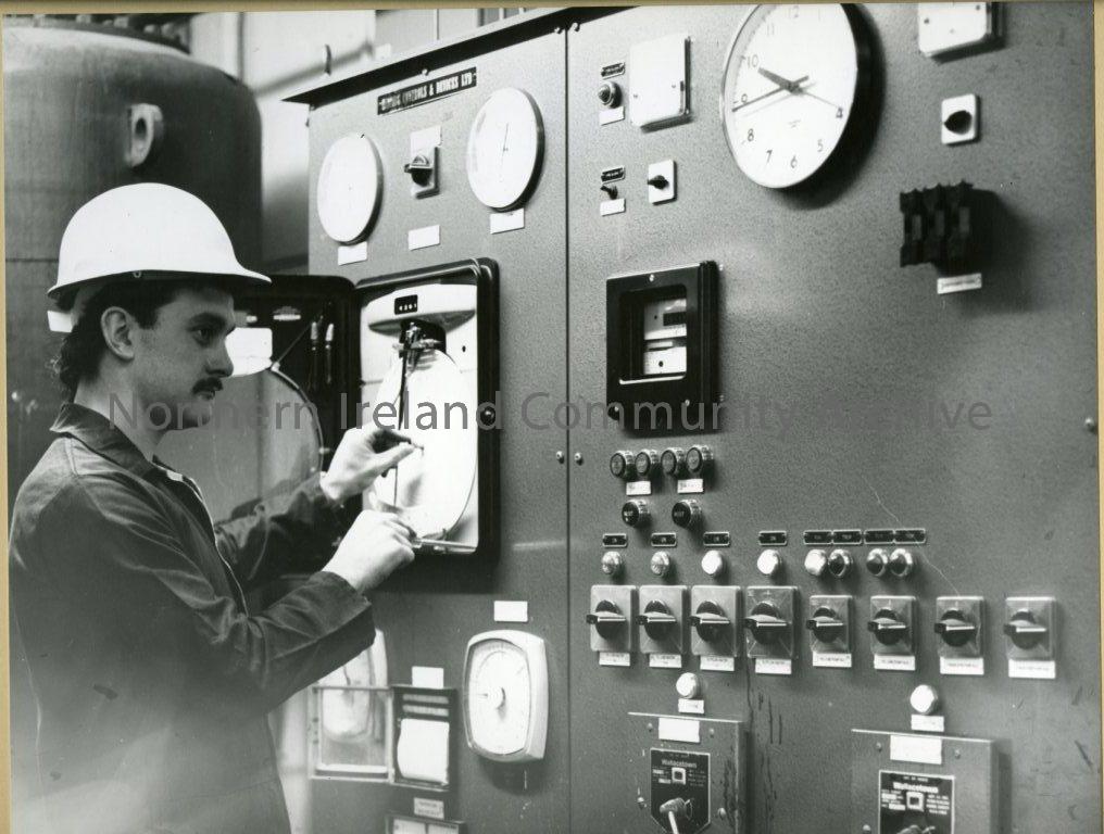black and white photograph of a man in plant room wearing a hard hat (6068)