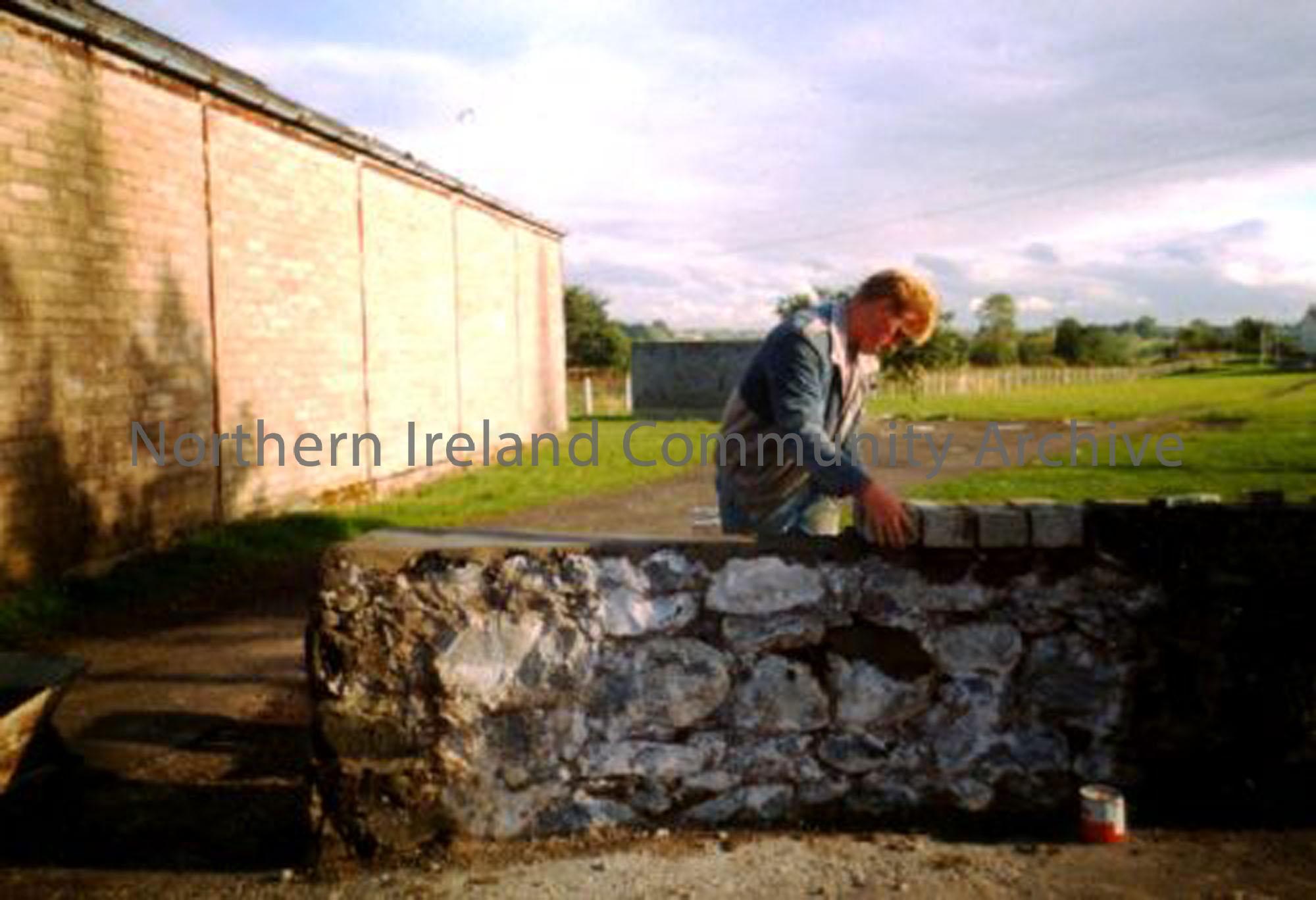 Christopher Mullholland attempting to rebuild a wall painting of King William III, originally built by Sandy Johnston, unfortunately it was never completed. Behind him is the old meal store, belonging to the Dervock Co.