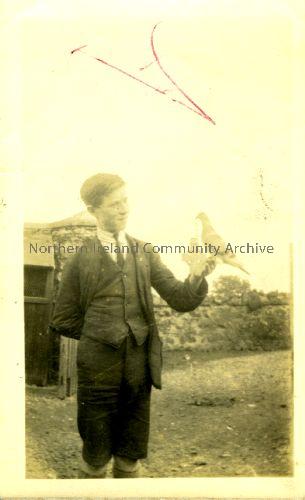 Patrick McErlain holding a pigeon. The McErlains were rabbit and poultry dealers whose house and business stood where the Castle Community Association building is now. (1943)