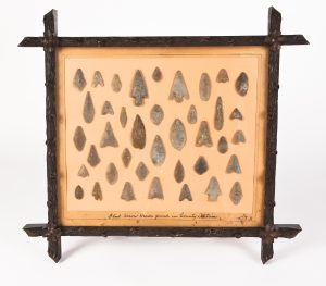 A collection Neolithic and Bronze Age arrowheads in an early 20th century frame from the Ballycastle Museum collection.