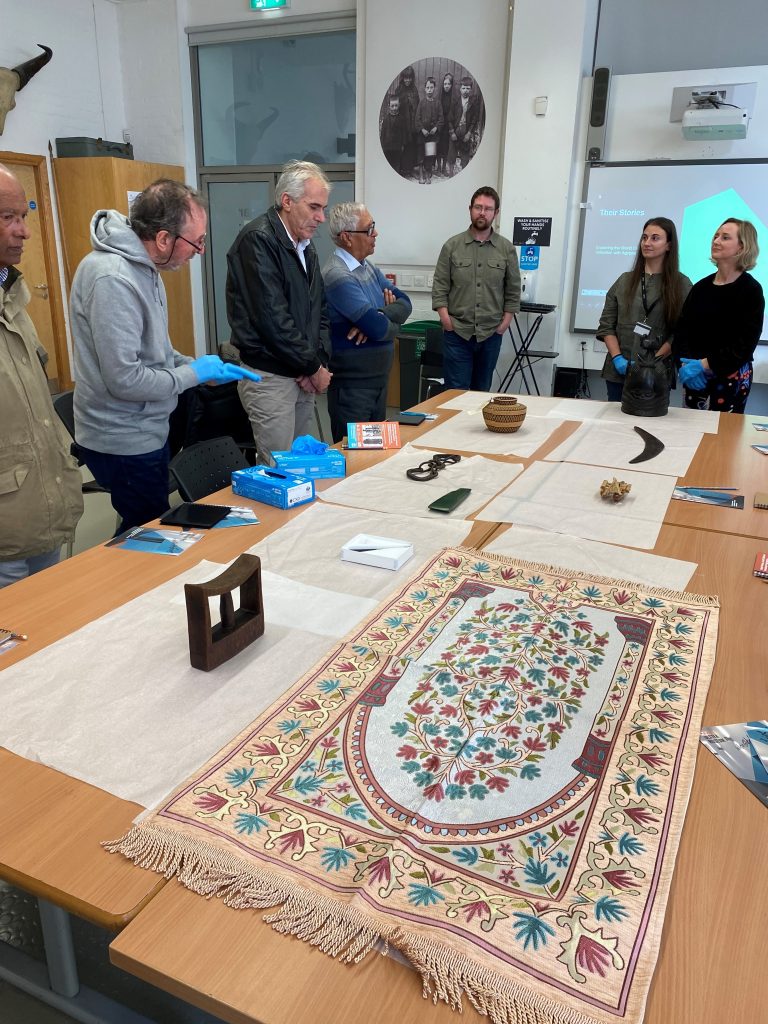 Participants in the GVLC programme at the Ulster Museum. Objects are laid out on a table in front of them.