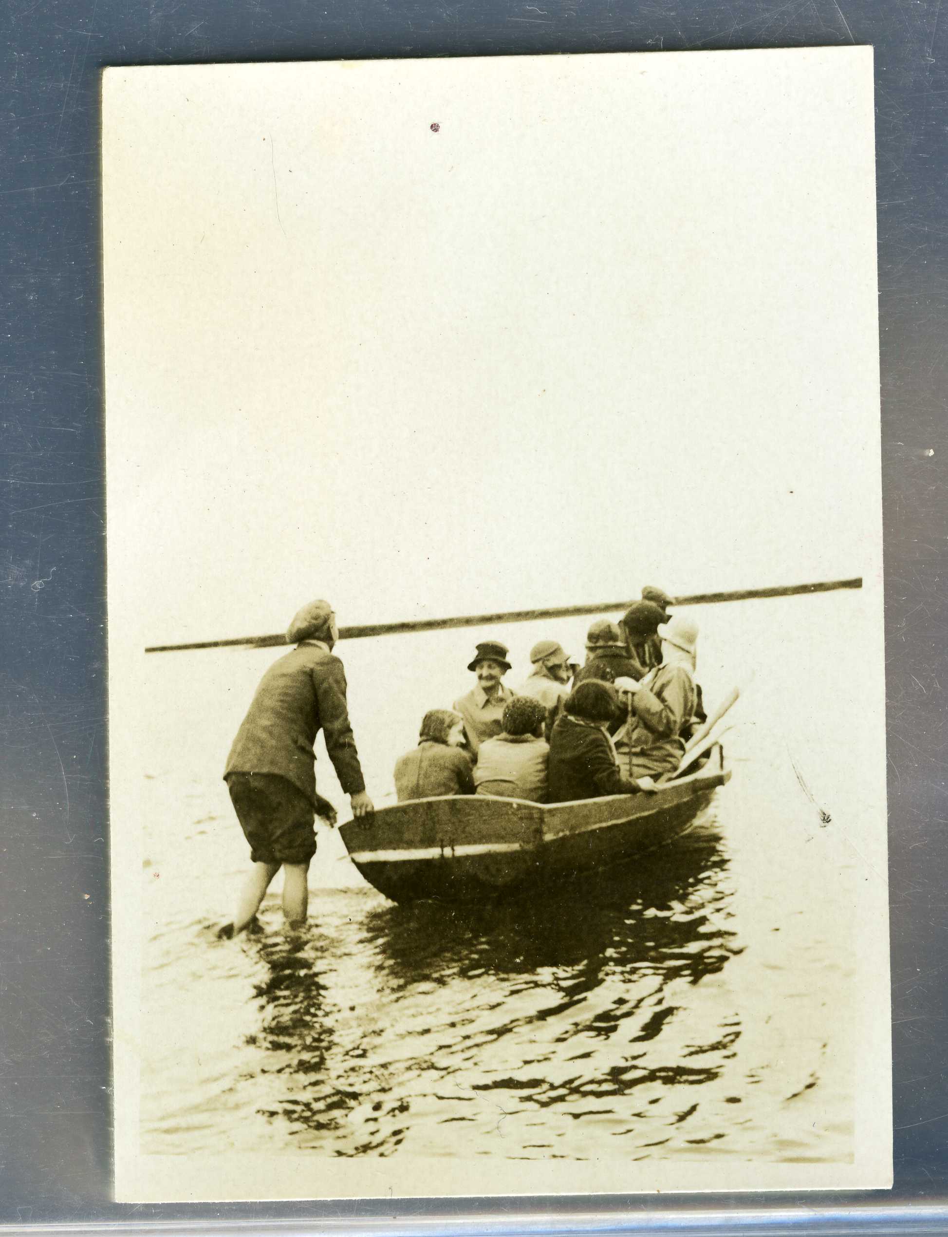 A boat full of people on a lake. A man is standing in the water ...